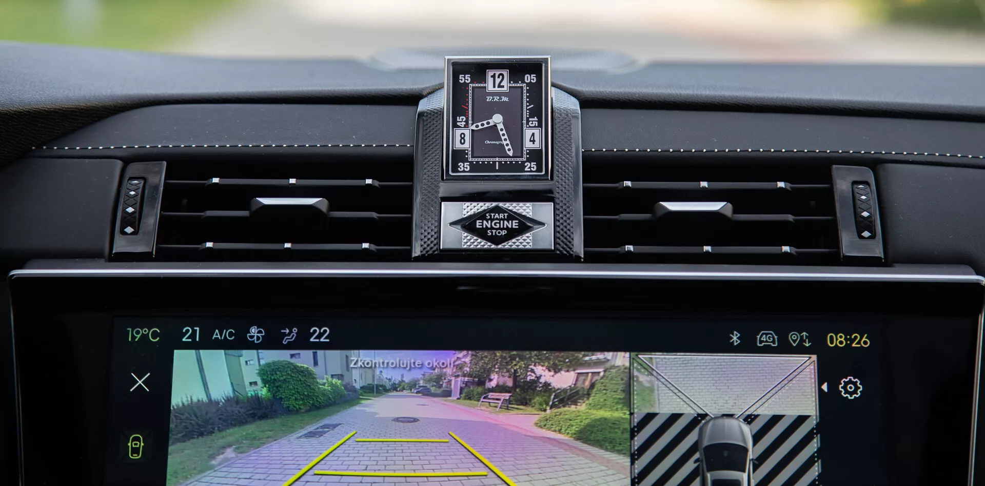 Vista interior del DS Automobiles DS-7 2022 mostrando el tablero, reloj analógico de lujo, y sistema central de infoentretenimiento con cámara trasera y función de asistencia al estacionar