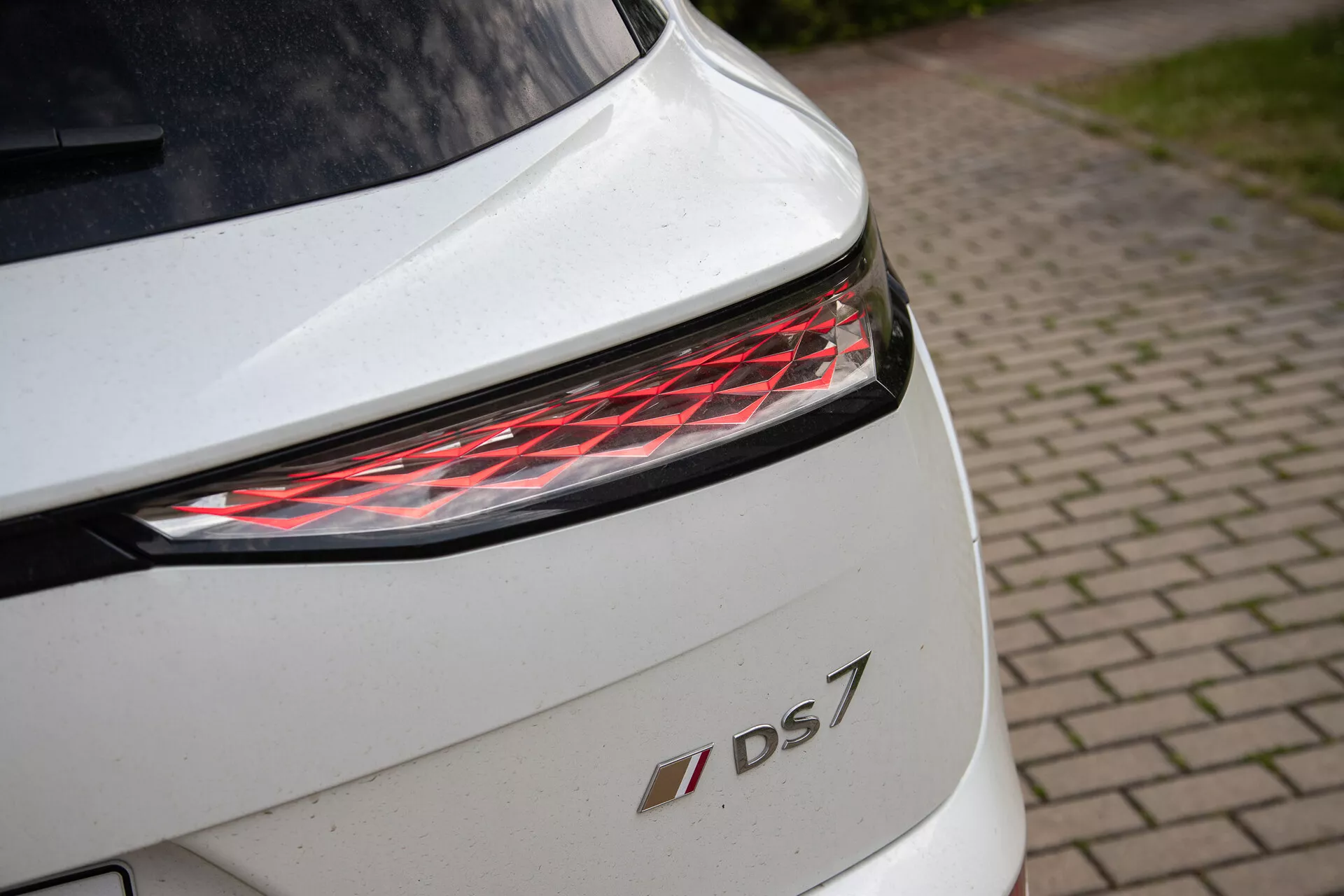 Primer plano de la sección trasera de un DS 7 blanco con luz trasera LED moderna y emblema del modelo, destacando los detalles de diseño y acabado premium