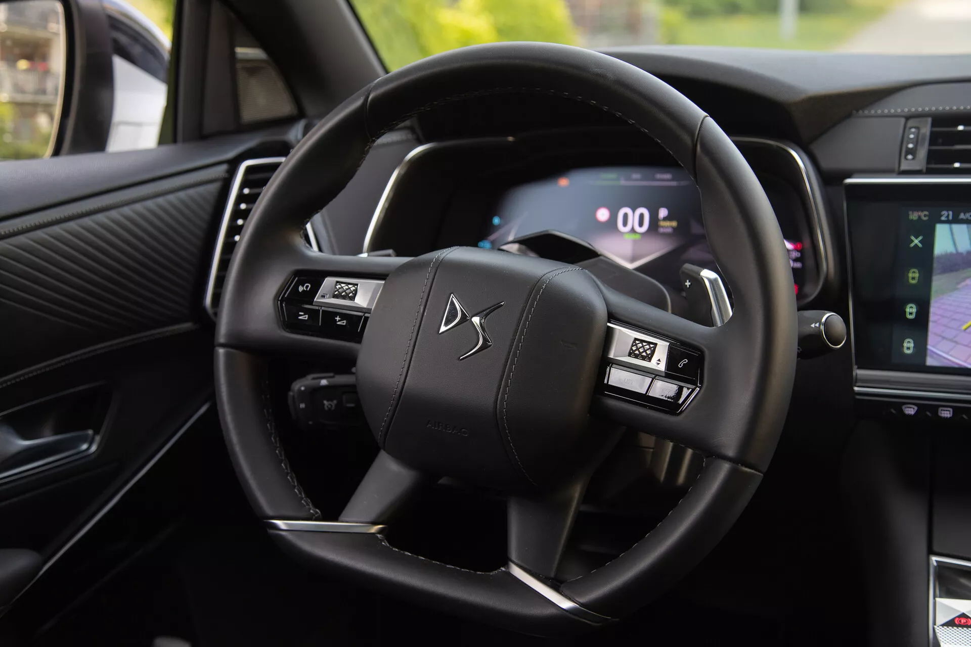 Vista interior del DS Automobiles DS-7 2022 mostrando el volante con botones multifunción y el cuadro de instrumentos digital, incluyendo levas de cambio y parte del sistema de infoentretenimiento mostrando la navegación