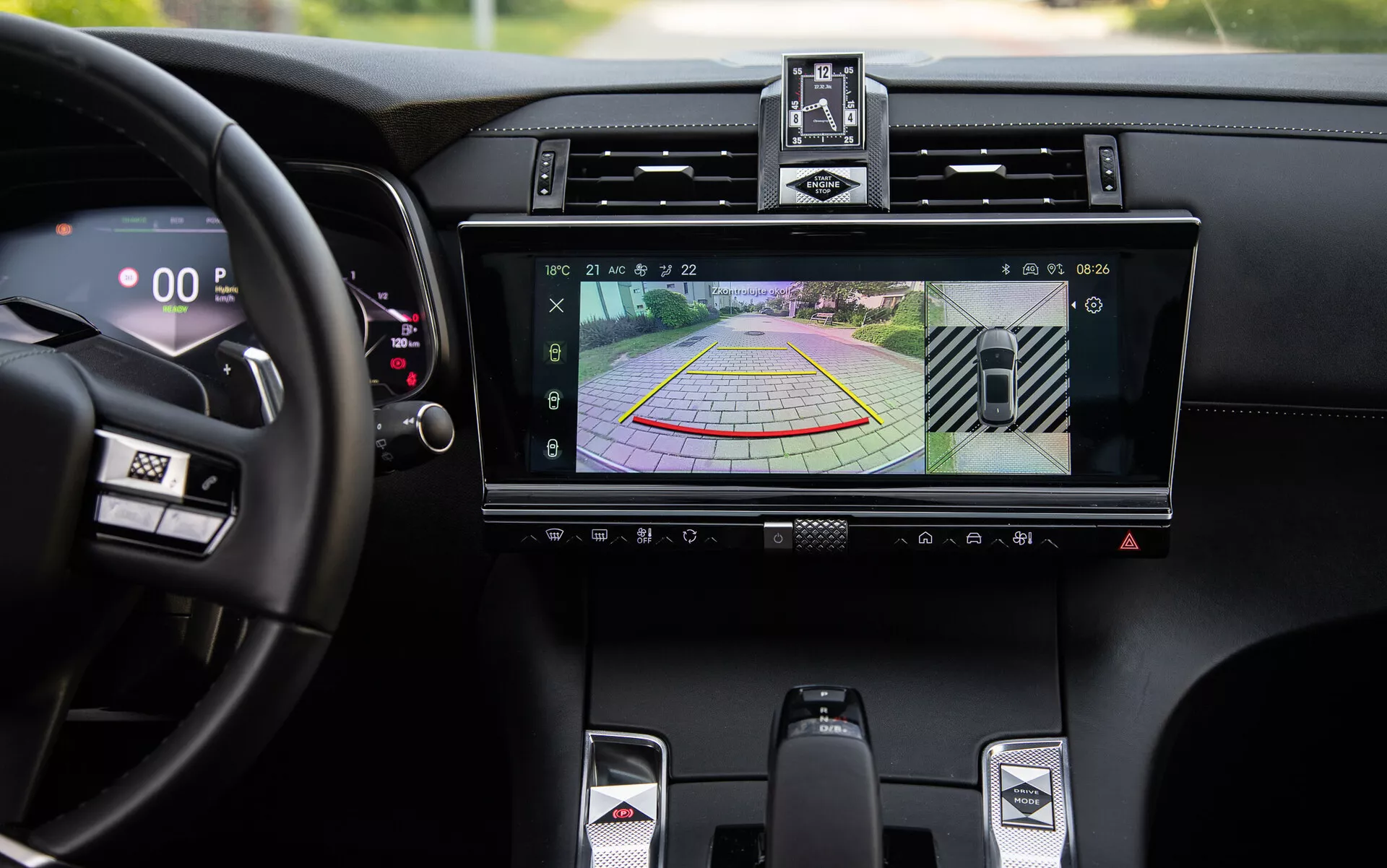 Detalle del lujoso interior del DS-7 2022 que muestra el sistema de infoentretenimiento con pantalla de cámara trasera y líneas guía dinámicas para asistencia de estacionamiento, rejillas de aire centrales, botones de control de clima, palanca de cambios deportiva y velocímetro digital