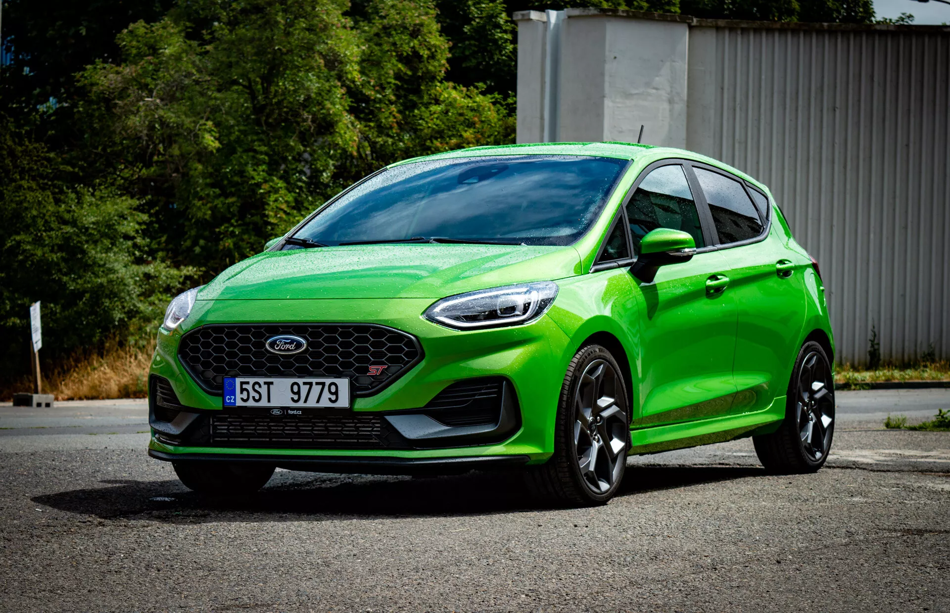 Hatchback Ford Fiesta 2022 de verde vibrante en vista frontal tres cuartos mostrando la parrilla frontal con emblema, parachoques deportivo con luces de niebla, faros angulares afilados, contornos aerodinámicos, grandes ruedas de aleación negras y sistema de iluminación moderno