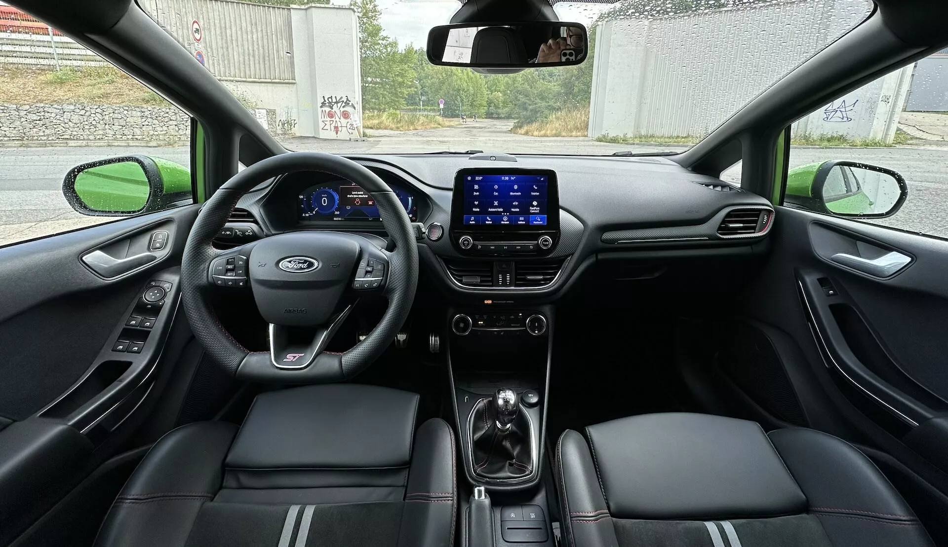 Vista interior del Ford Fiesta 2022 desde el asiento trasero, mostrando el cockpit completo con tablero digital, volante multifunción y asientos de cuero con detalles de costura