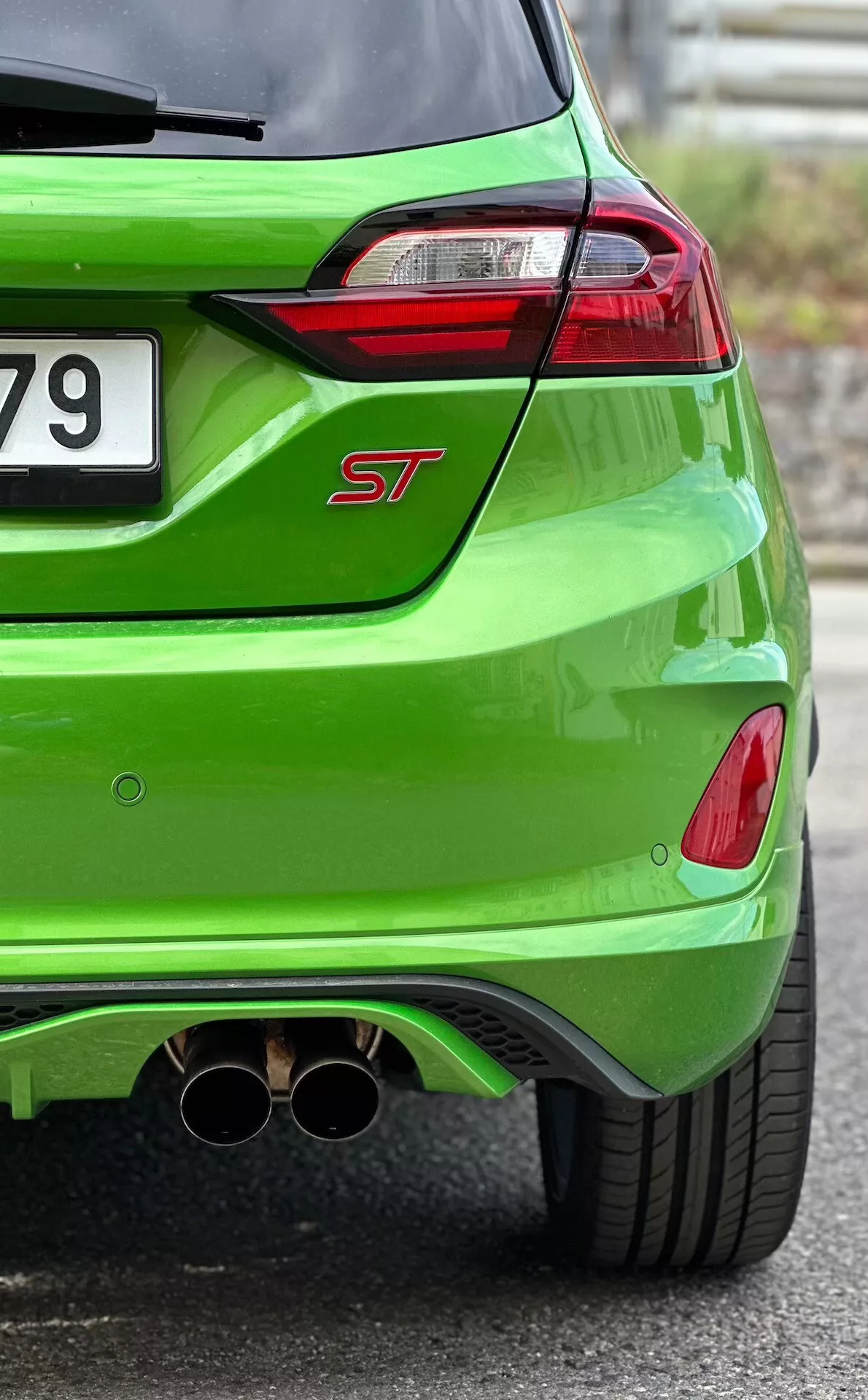 Vista detallada del trasero del Ford Fiesta ST 2022 en acabado metálico verde brillante, mostrando luces traseras LED, escape doble cromado y difusor trasero aerodinámico
