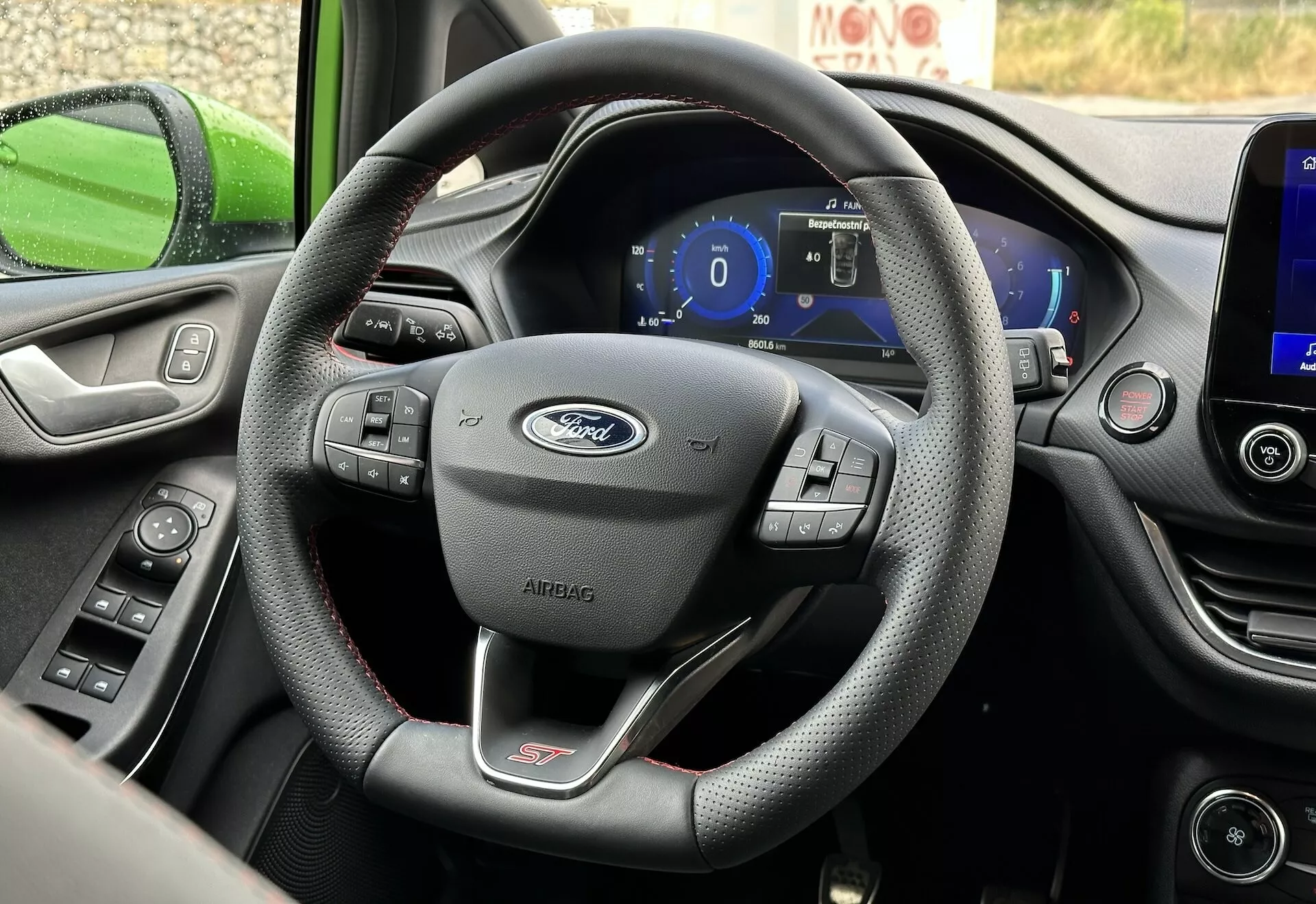 Vista interior del Ford Fiesta 2022 centrada en el volante de tres radios envuelto en cuero con controles multifunción y tablero digital desde la perspectiva del asiento del conductor