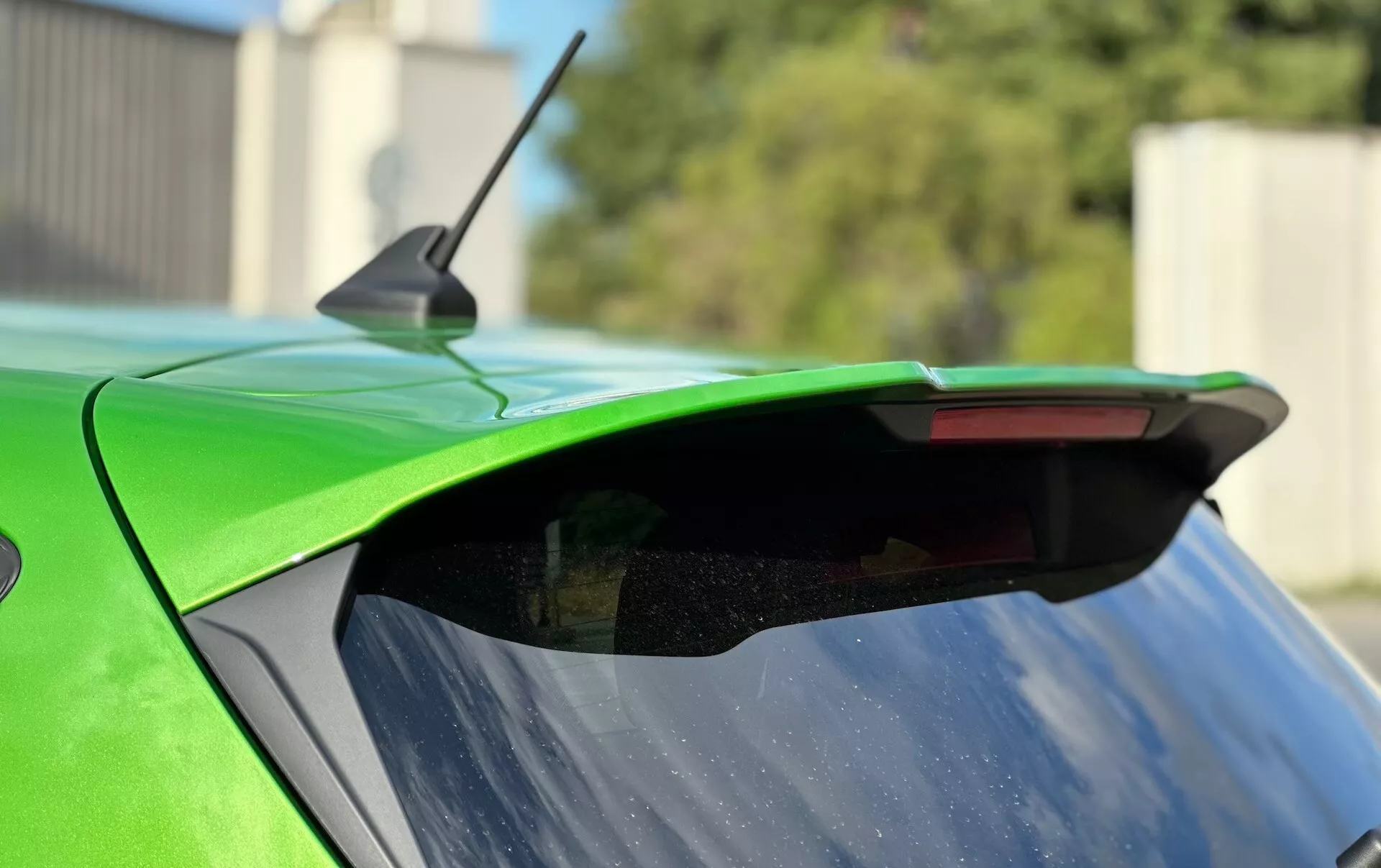 Primer plano del extremo trasero de un Ford Fiesta 2022 subrayando el alerón aftermarket, pintura verde vibrante e luz de freno integrada