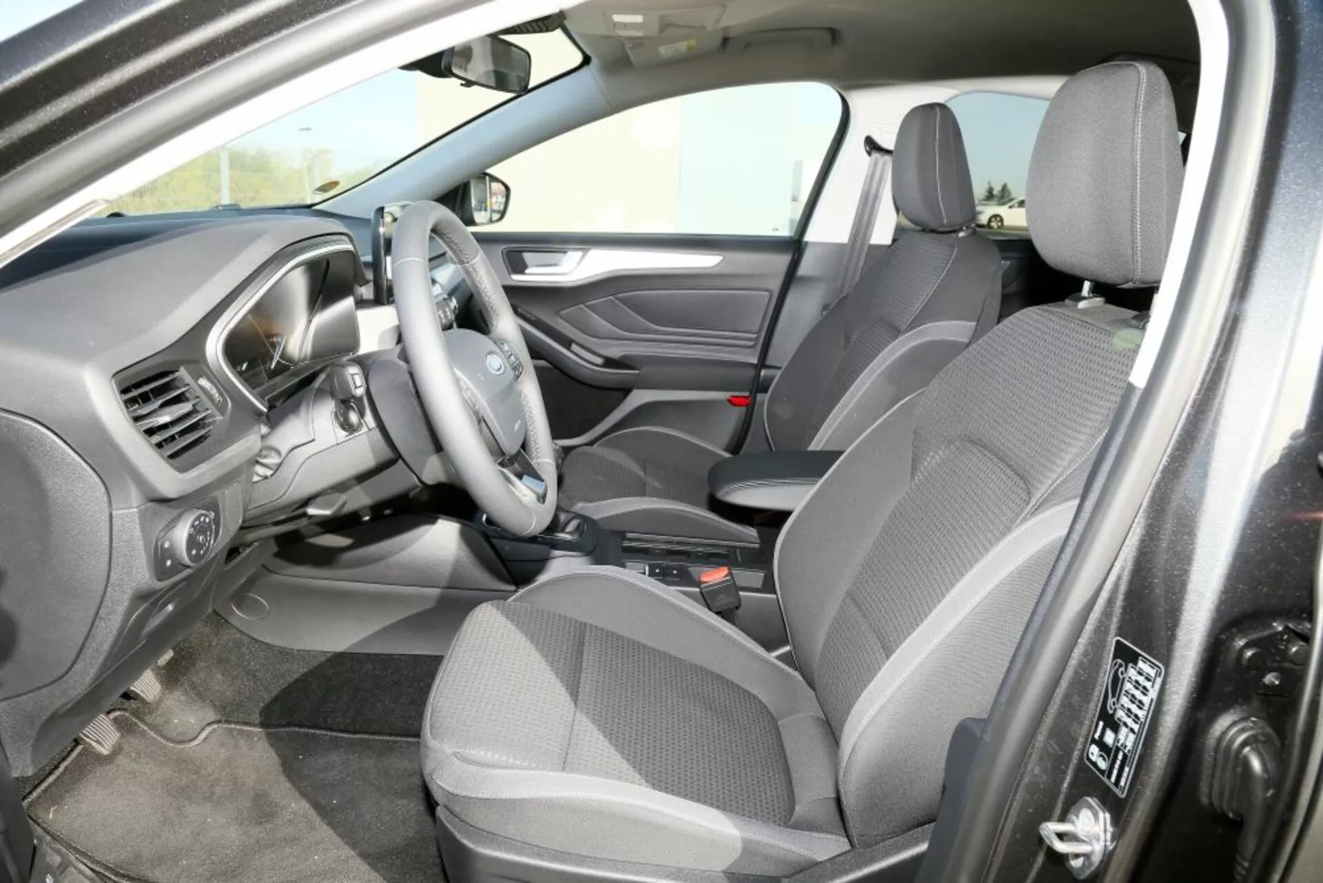Vista interior del Ford Focus 2013 desde la perspectiva del pasajero delantero mostrando asientos de tela, disposición de conducción a la derecha y la consola central con transmisión automática