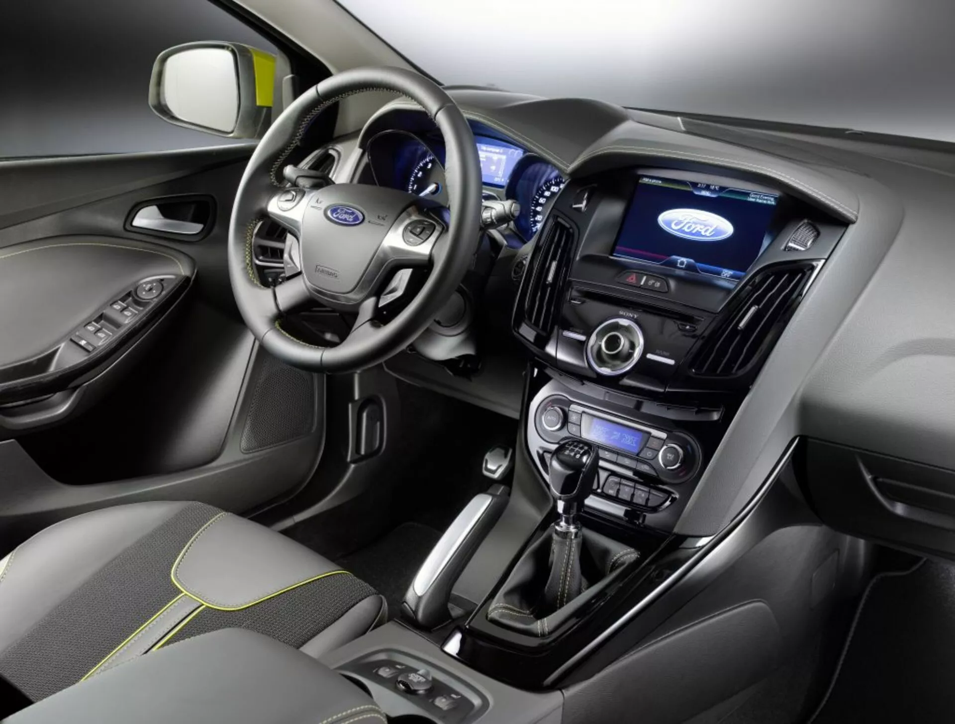 Vista interior de un Ford Focus 2011 con el tablero de mando, área del conductor, volante con logo de Ford, panel de instrumentos iluminado, pantalla táctil central de infotenimiento, controles de clima, sistema de audio, palanca de cambios automática y asiento del pasajero delantero con cubierta de tela y patrón de costura