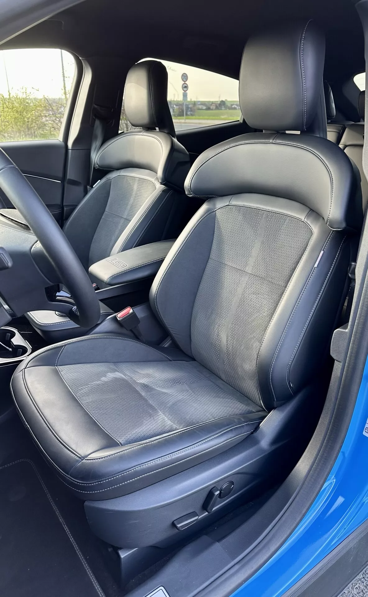 Interior del Ford Mustang Mach-E 2020 mostrando el asiento del conductor con tapicería de cuero y tela, ajuste electrónico del asiento y cinturón de seguridad
