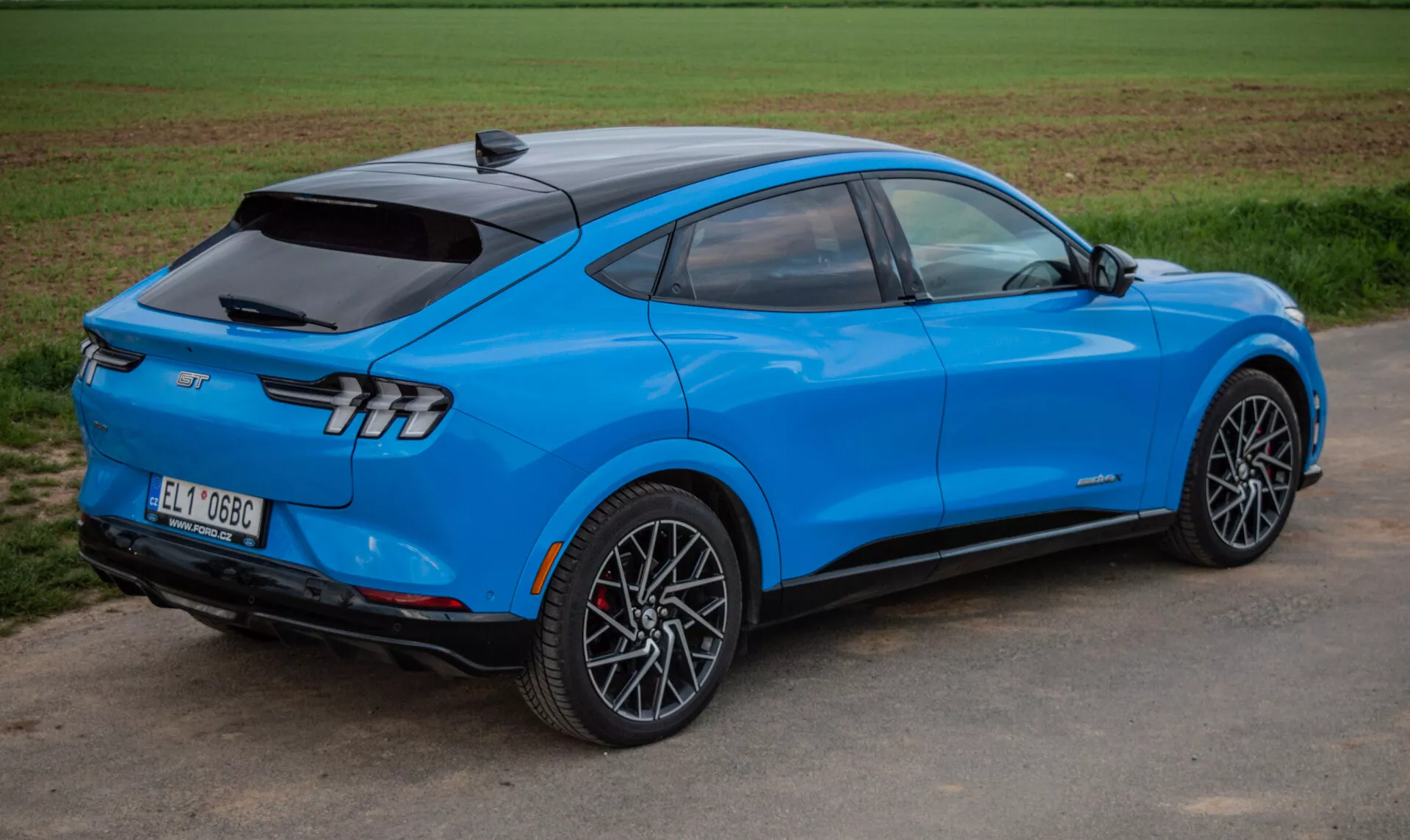 SUV eléctrico Ford Mustang Mach-E 2020 en azul brillante en una vista trasera dinámica de tres cuartos destacando el diseño aerodinámico, luces traseras elegantes y ruedas de aleación deportivas, mostrando tecnología avanzada y propulsión eléctrica.