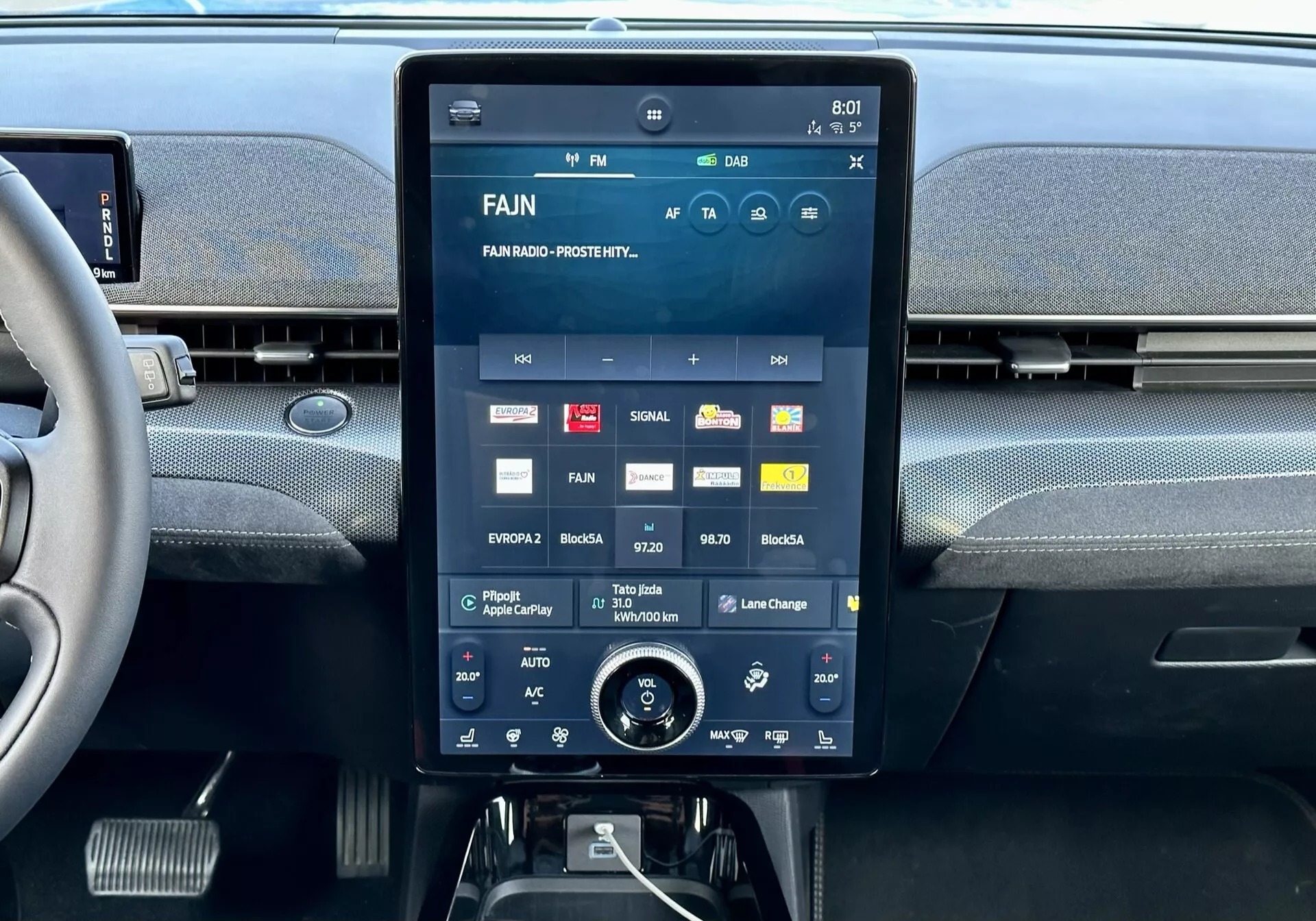 Consola central interior del Ford Mustang Mach-E 2020 con una gran pantalla táctil que muestra la interfaz multimedia con aplicaciones y configuraciones, rejillas de ventilación integradas arriba y un dial rotatorio adicional para el control del clima abajo.