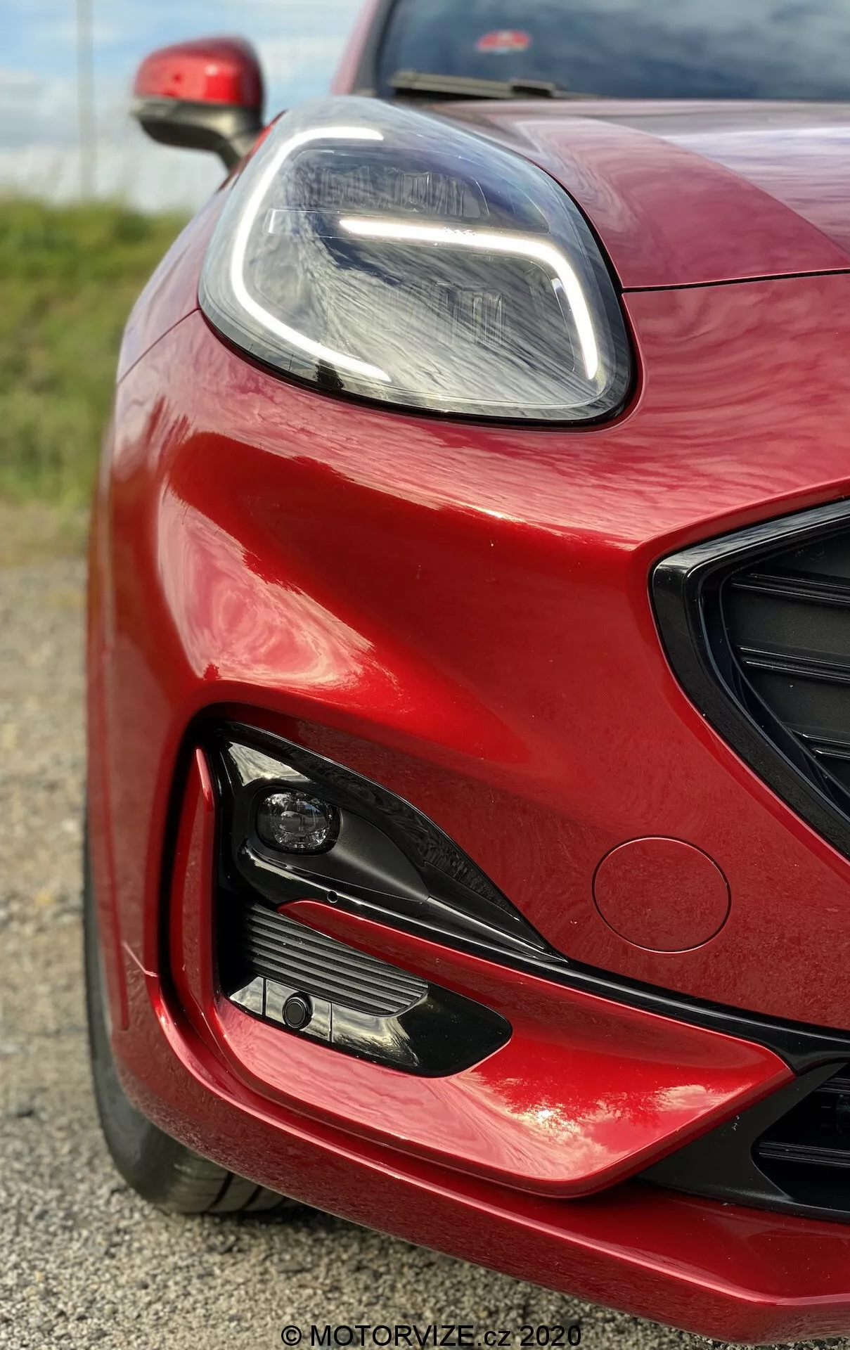 Primer plano de la parte frontal izquierda de un Ford Puma 2020 en color rojo vibrante con acabado brillante, mostrando el faro LED elegante, grandes tomas de aire y luz antiniebla, destacando su diseño moderno y orientado al rendimiento.