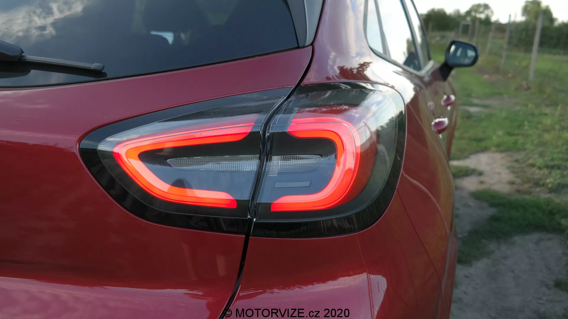 Detalle en primer plano de la sección trasera del Ford Puma 2020, destacando la distintiva luz trasera LED en forma de C iluminada. Capturada desde un ángulo de tres cuartos traseros, la imagen resalta la avanzada tecnología de iluminación y el diseño moderno, con la marca de agua 'MOTORVIZE.cz 2020' indicando su fuente.