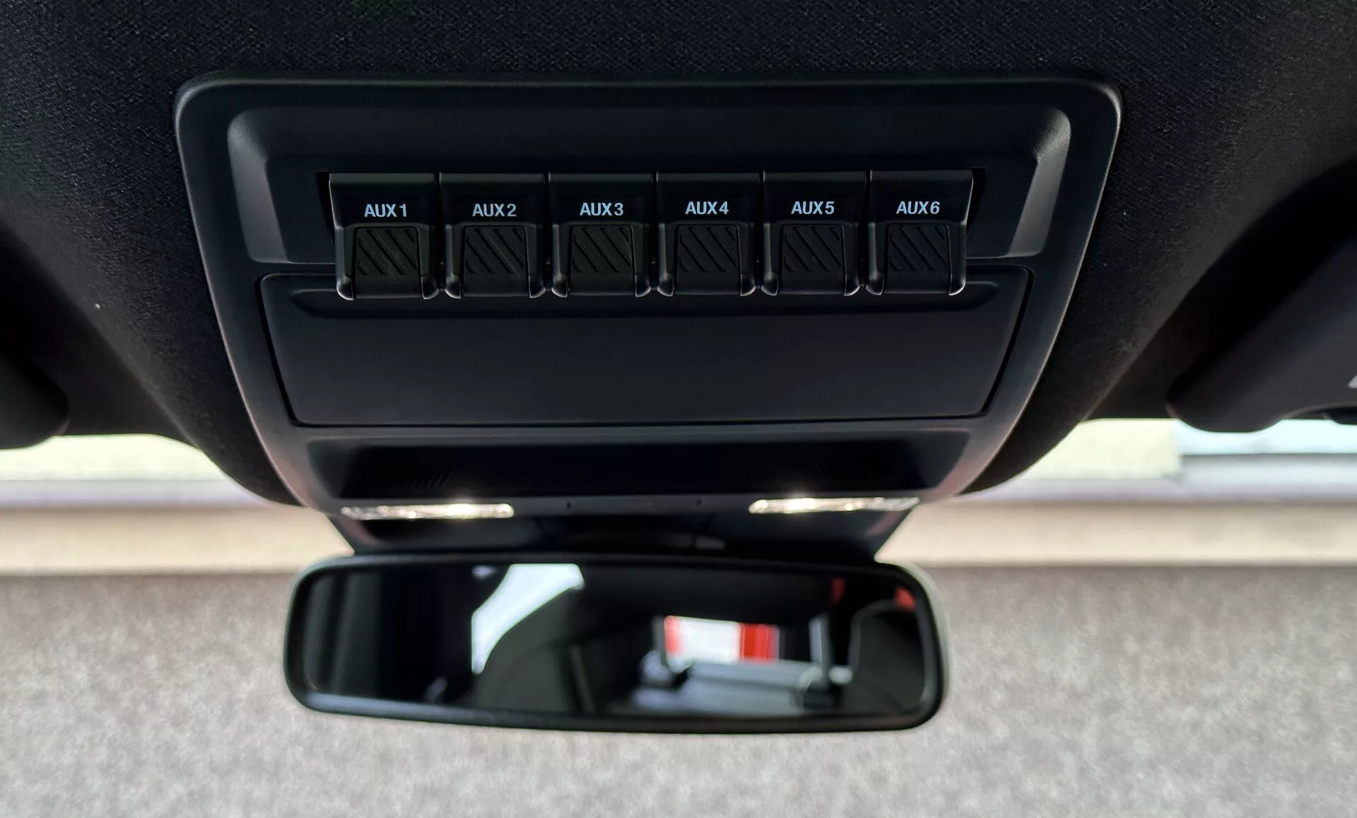 Vista detallada del interior de un Ford Ranger 2022, enfocándose en los interruptores auxiliares etiquetados de AUX1 a AUX6 en la consola superior y el espejo retrovisor estándar desde la perspectiva del conductor