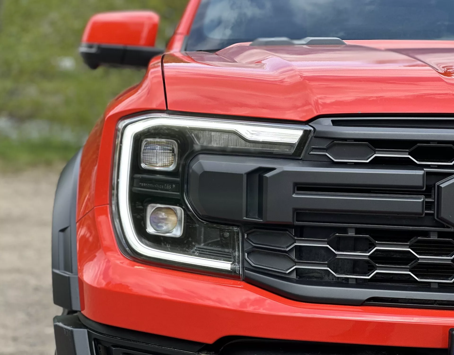 Vista cercana de la esquina frontal del Ford Ranger 2022 mostrando parrilla hexagonal, conjunto de faros detallados y capó contorneado en rojo