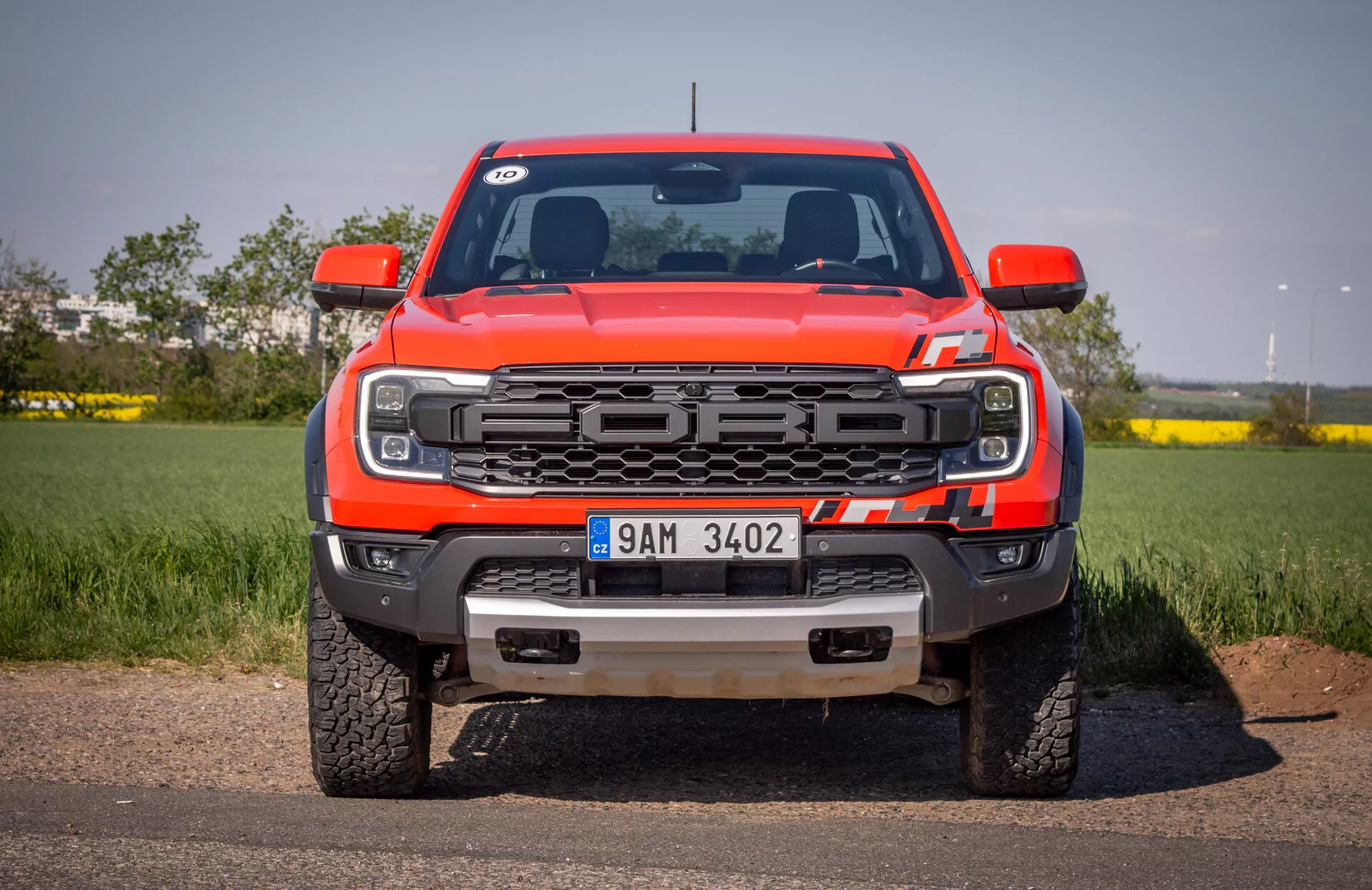 Vista frontal de camioneta roja Ford Ranger 2022 sobre asfalto con fondo de cielo despejado, destacando parrilla, faros LED, parachoques delantero con ganchos de remolque y placa protectora, y logo de Ford
