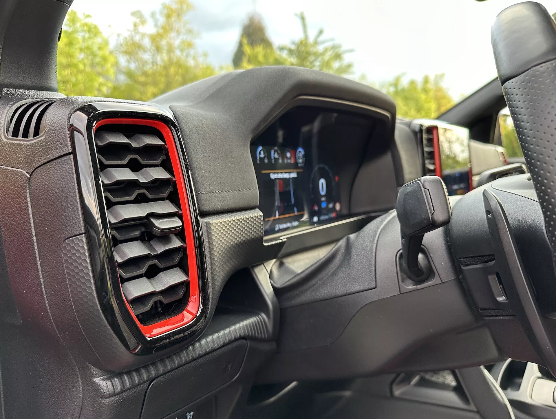 Vista interior del Ford Ranger 2022 desde la perspectiva del conductor, mostrando el cuadro de instrumentos digital y la ventilación izquierda con acentos rojos, con un ángulo ligeramente descentrado hacia el volante que sugiere giro