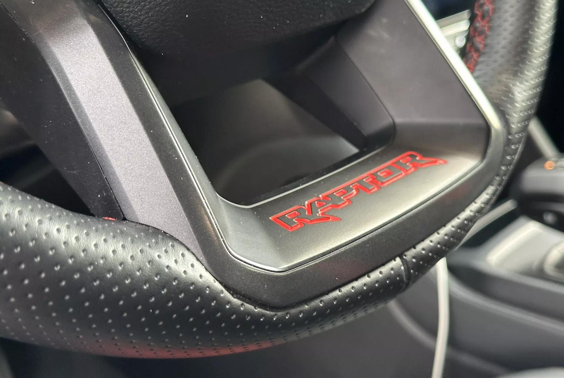 Vista de cerca de un volante de Dodge Viper mostrando el cuero perforado con costuras rojas y el emblema 'Viper', indicando un interior de coche deportivo y lujoso.