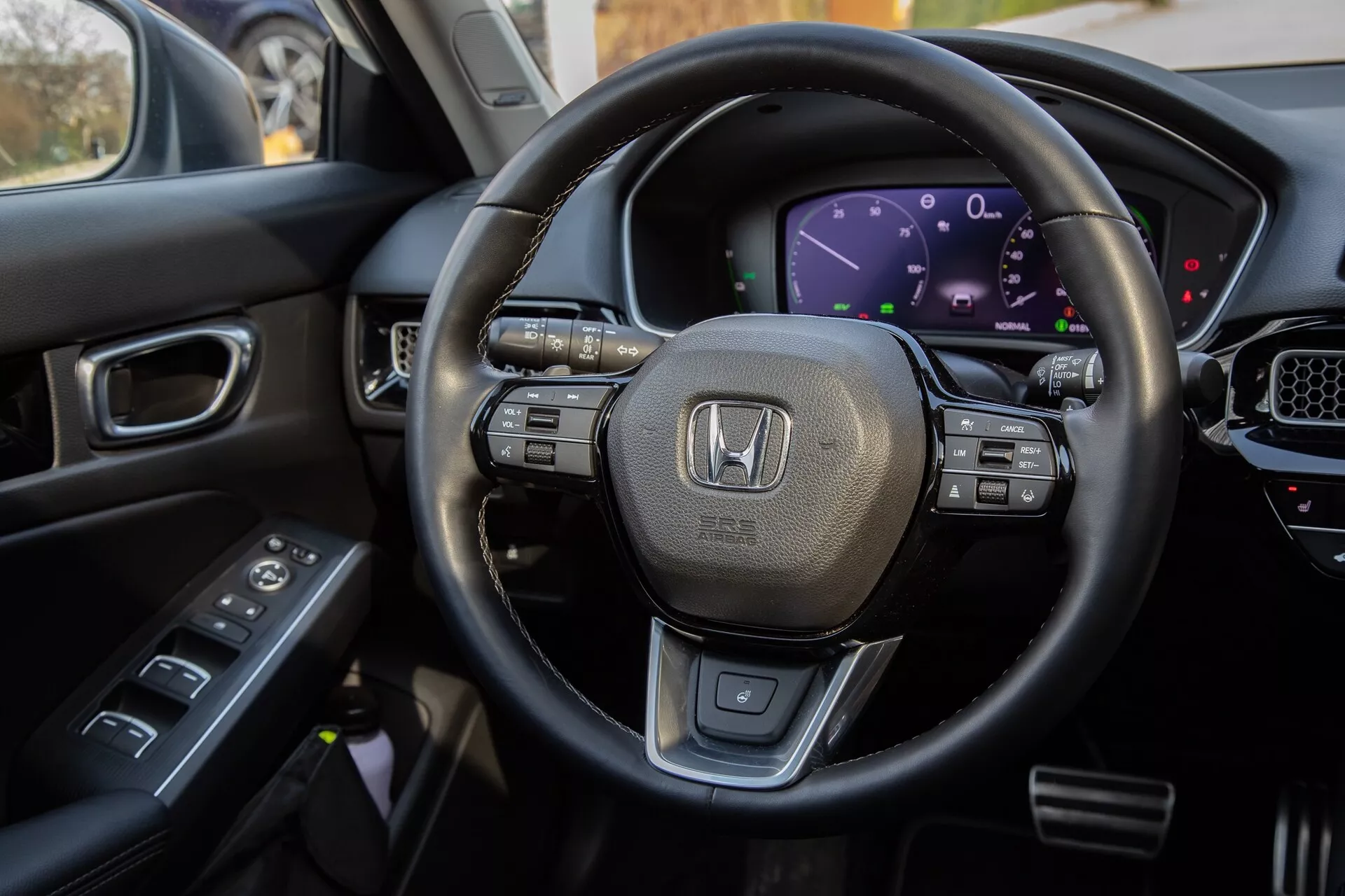 Vista interior del Honda Civic 2022 desde el asiento del conductor, destacando el volante forrado en cuero con controles multifuncionales, el cuadro de instrumentos digital, parte de la consola central con pantalla táctil y controles en la puerta del conductor para una exhibición integral de las características tecnológicas modernas y diseño lujoso del vehículo.