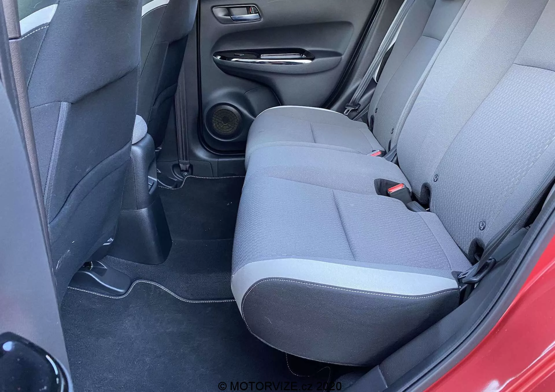Vista del interior del Honda Jazz 2020 (Jazz-Crosstar), mostrando el área de los asientos traseros desde un ángulo ligeramente elevado, destacando la tapicería de tela bicolor, el sistema de altavoces y los elementos de diseño prácticos.