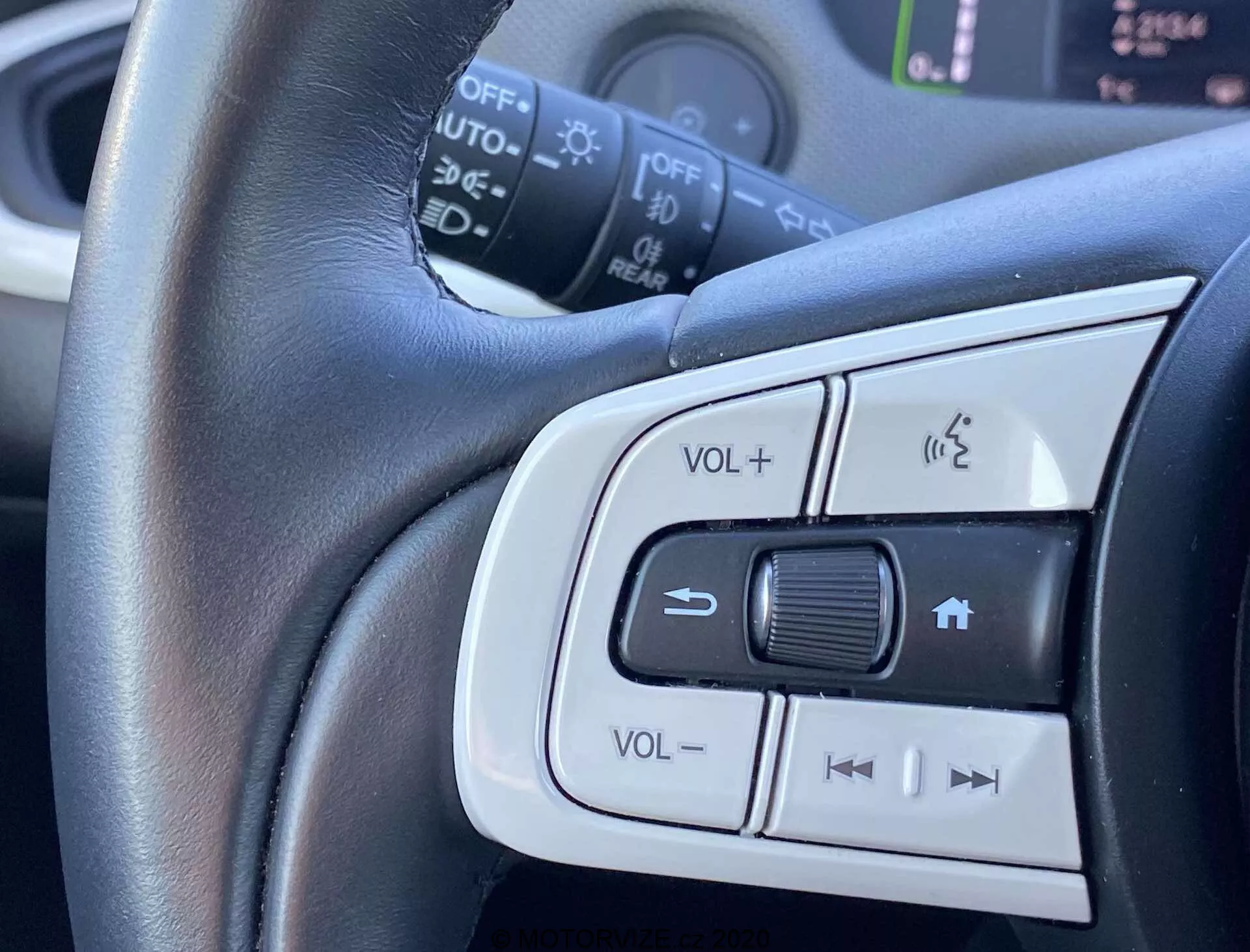 Vista en primer plano de los controles montados en el volante del Honda Jazz Crosstar 2020, mostrando el ajuste de volumen, el sistema de teléfono manos libres y los botones de posible control de crucero o selección de pistas de audio. Enfoque central en el volante de cuero con adornos plateados destacando la comodidad y el diseño elegante.