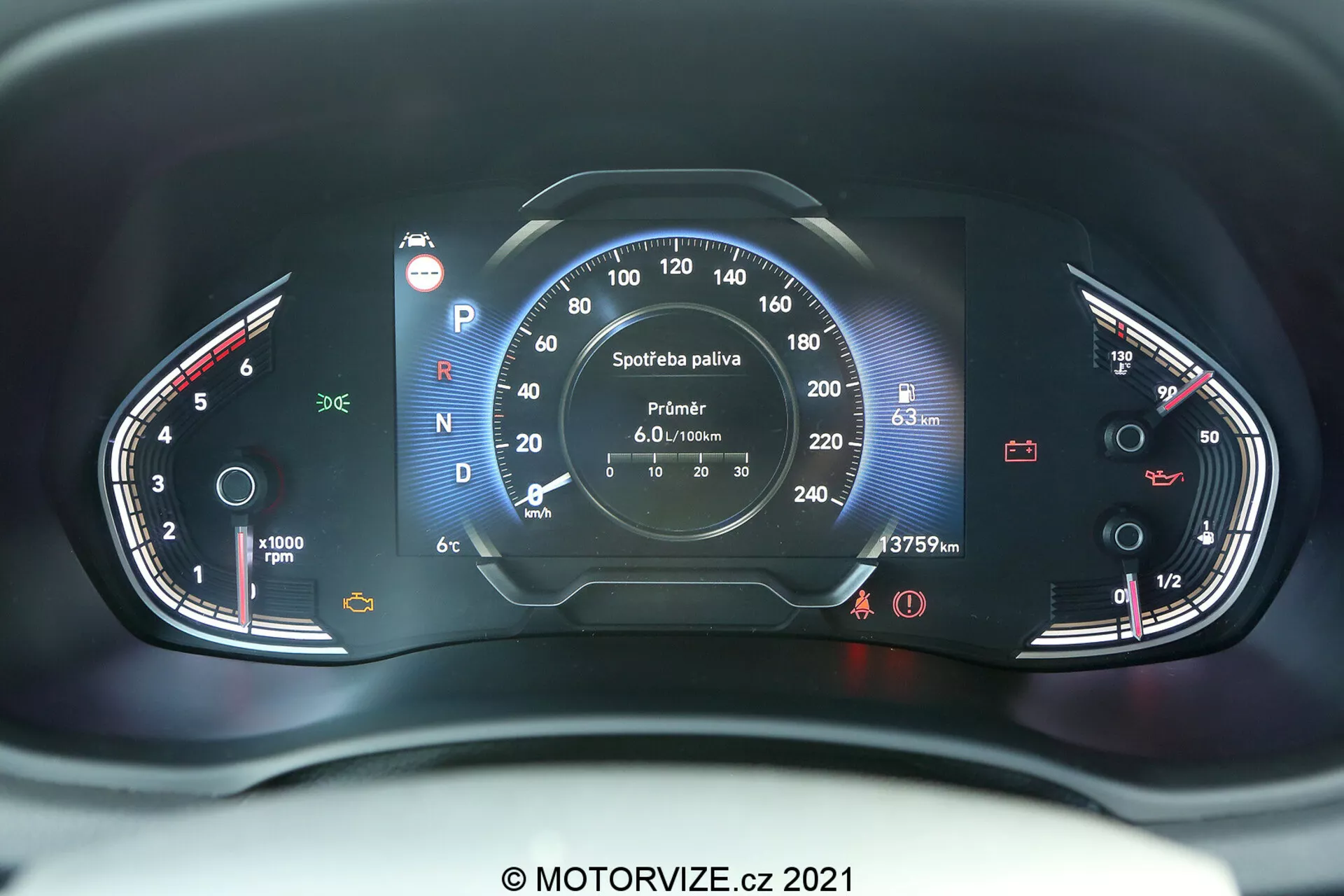 Vista de cerca del tablero de instrumentos del Hyundai i30 2020 desde la perspectiva del asiento del conductor. La imagen captura un ángulo centrado, revelando elementos tanto analógicos como digitales. La parte izquierda presenta un tacómetro que alcanza hasta 8,000 RPM con un pequeño indicador de temperatura. El lado derecho incluye un velocímetro que escala hasta 260 km/h y un indicador de combustible. La pantalla digital central muestra información como la selección de marchas (la marcha actual es Parking), lectura del odómetro (37579 km), velocímetro digital (---- km/h) y detalles del computadora de viaje sobre el consumo de combustible y el rango restante. El tablero está iluminado con luces rojas y blancas, mejorando la visibilidad y preservando la visión nocturna. La imagen presenta una marca de agua 'MOTORVIZE.cz 2021'.