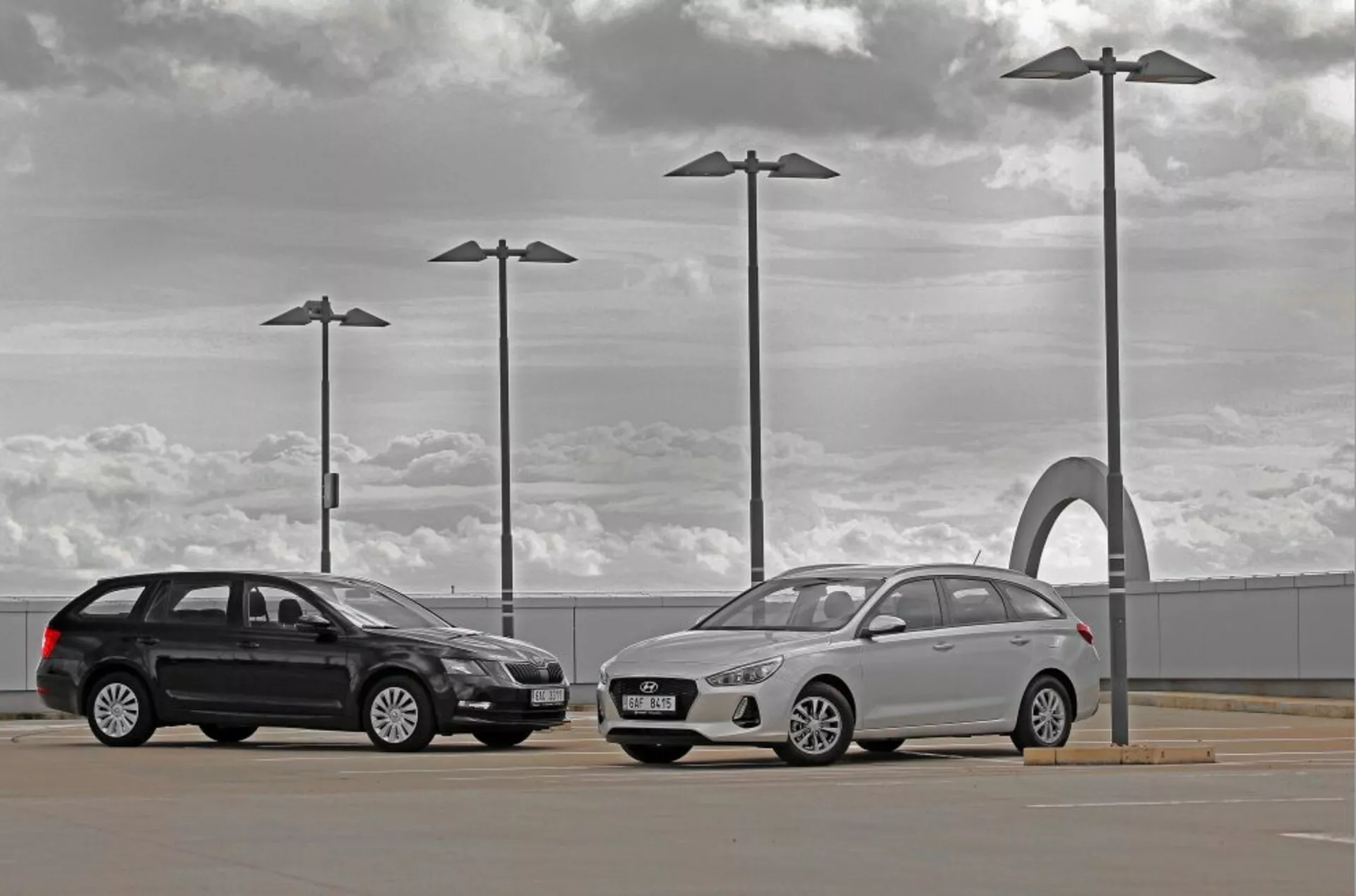 Hyundai i30 2017 familiar y sedán en un aparcamiento exterior bajo un cielo nublado con elementos de diseño urbano