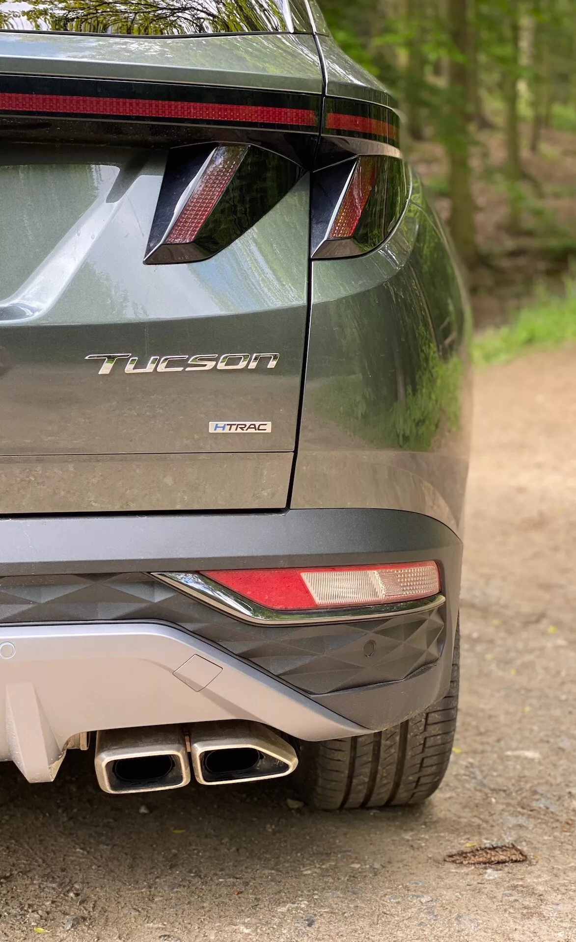 Vista parcial trasera del Hyundai Tucson modelo 2020 indicando que es la versión 1.6 T-GDi Pure, mostrando el lado derecho del parachoques, luz trasera parcial, alerón trasero con luz de freno LED, salidas de escape dobles y la insignia del modelo con el nombre 'Tucson' y la tecnología de motor 'T-GDi'.