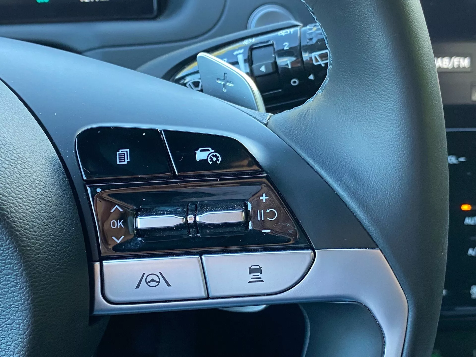 Vista de cerca de los controles montados en el volante en el lado izquierdo de un Hyundai Tucson 1.6 T-GDI Pure del 2020, que muestra características como navegación por menús, control de volumen de audio, activación de comandos de voz y funcionalidad de llamadas por Bluetooth.