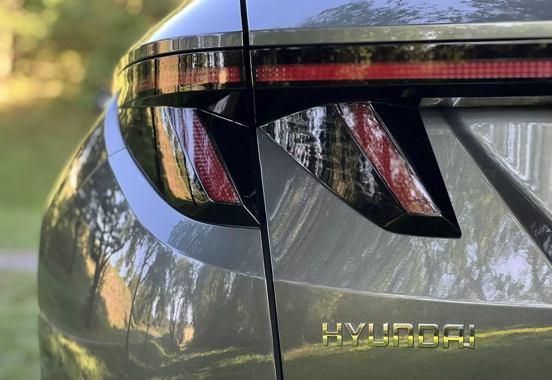 Vista detallada de la sección trasera del Hyundai Tucson 2020, mostrando luces traseras LED angulares, marca HYUNDAI, alerón trasero integrado con luz de freno y acabado metálico brillante