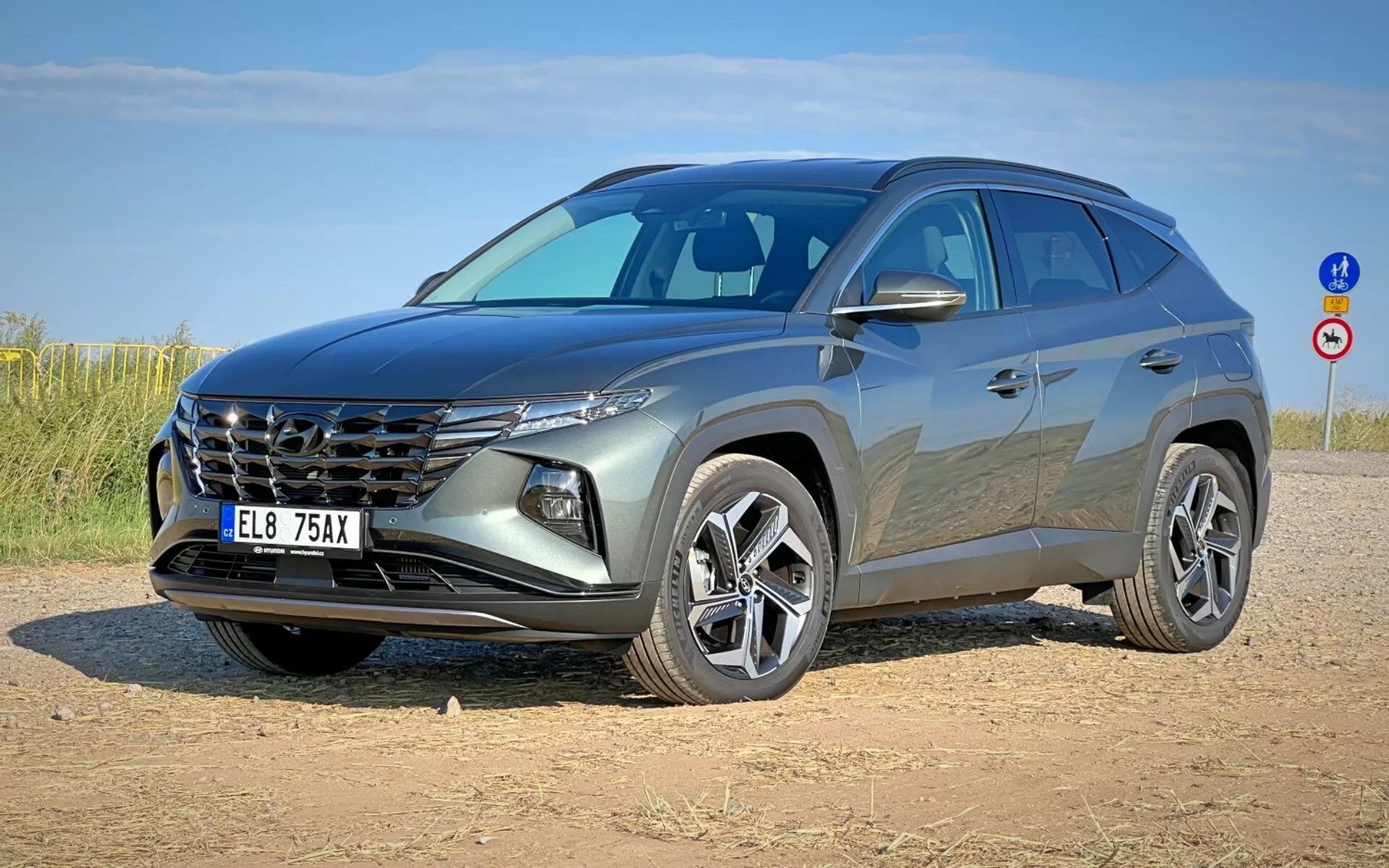 SUV moderno Hyundai Tucson 2020 en vista frontal tres cuartos mostrando su parrilla distintiva, faros elegantes, fascia frontal, capó esculpido y ruedas de aleación en una salida de tierra bajo cielo despejado
