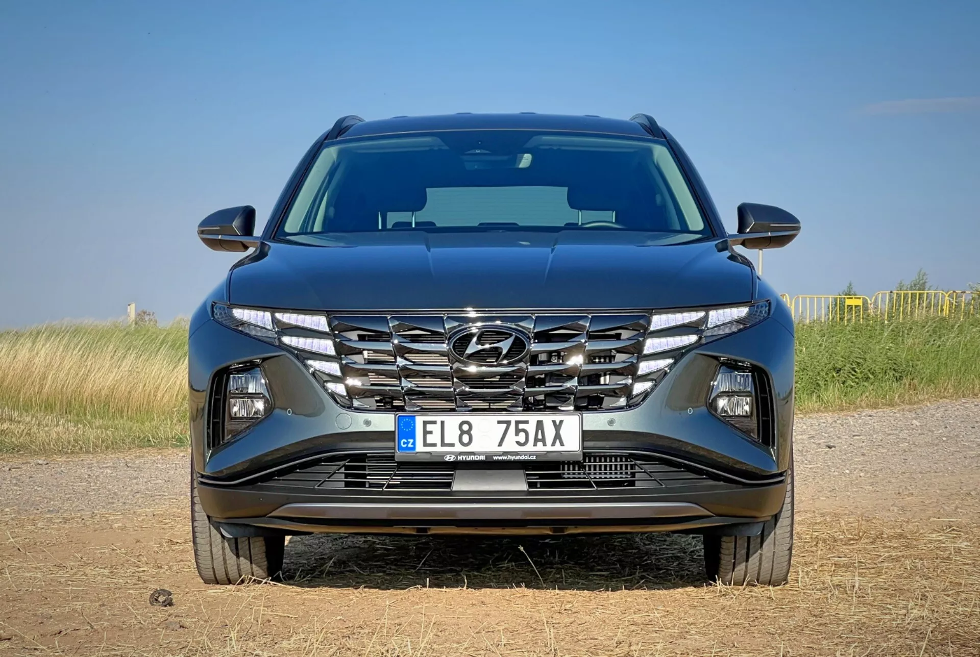 Vista frontal del Hyundai Tucson 2020 mostrando diseño aerodinámico del capó, parrilla en cascada, faros LED afilados y parachoques detallado con posibles características tecnológicas, situado sobre un fondo de paisaje natural