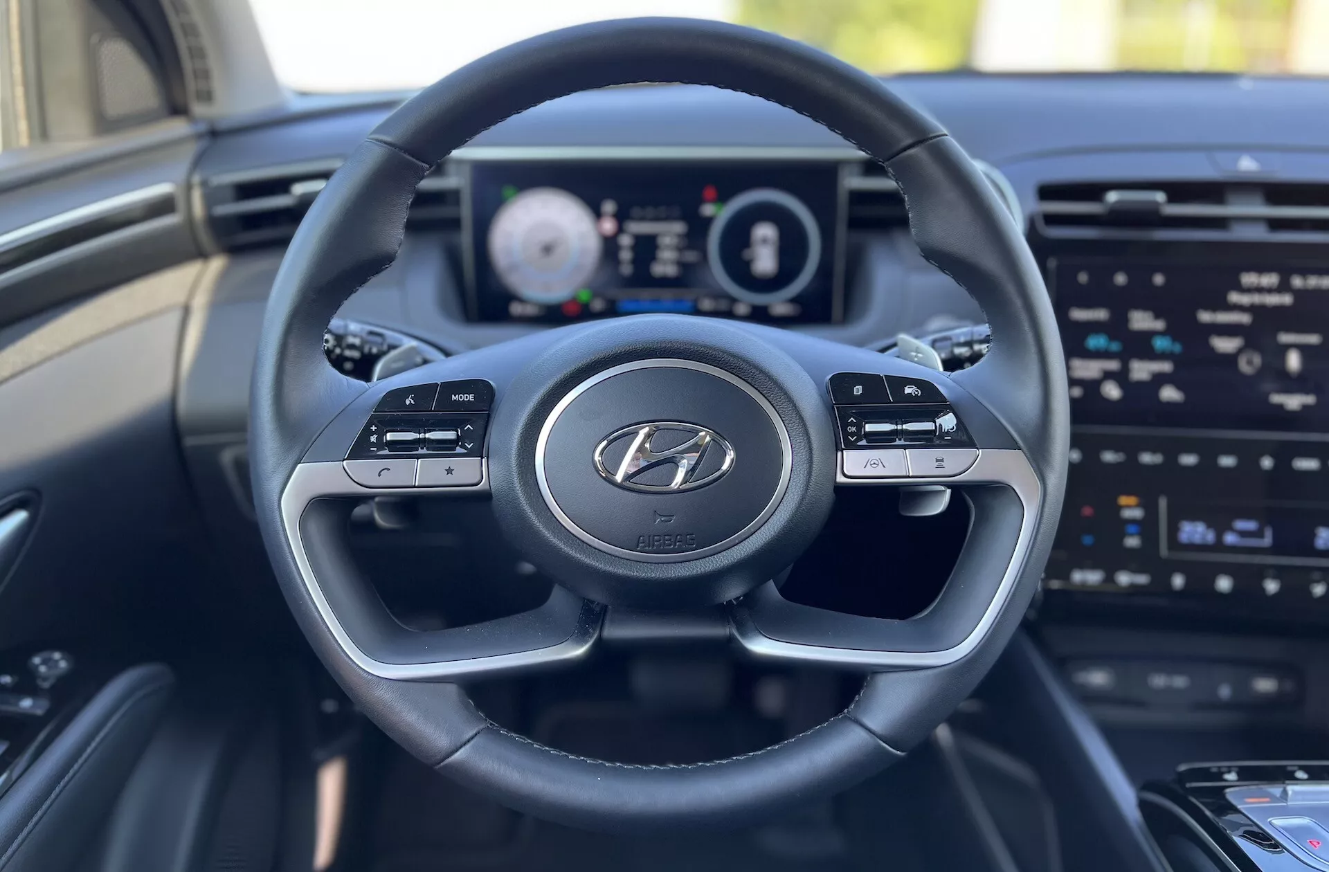 Vista interior del Hyundai Tucson 2020 desde el asiento del conductor mostrando el volante con el logo de Hyundai, el cuadro de instrumentos digital y la pantalla de entretenimiento