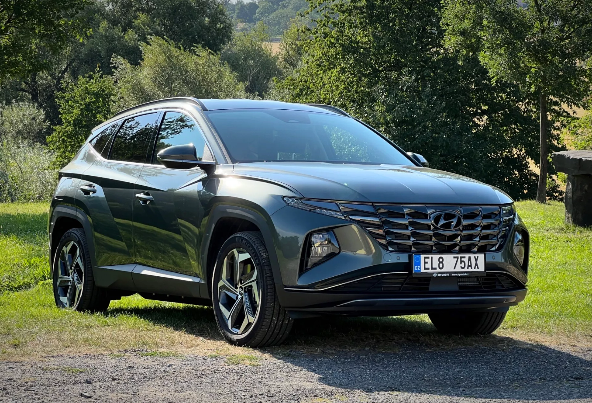 Hyundai Tucson 2020 estacionado sobre césped con fondo de campo, mostrando perspectiva frontal de tres cuartos para una vista detallada de sus elegantes faros LED, parrilla frontal angular y acabado oscuro y brillante