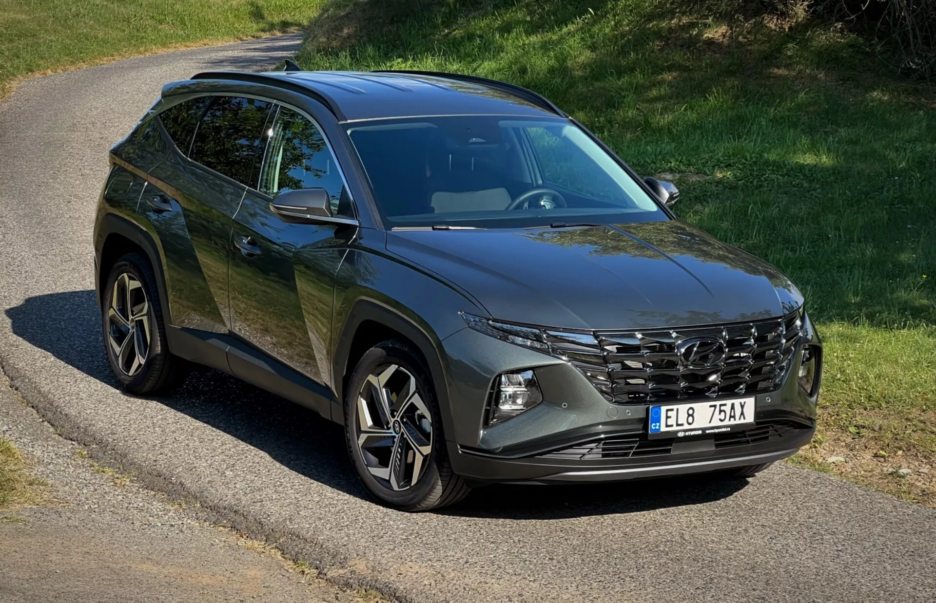 SUV Hyundai Tucson 2020 estacionado en un camino solitario mostrando su parrilla frontal, faros LED, ruedas de aleación y líneas de carrocería bajo la luz natural del sol