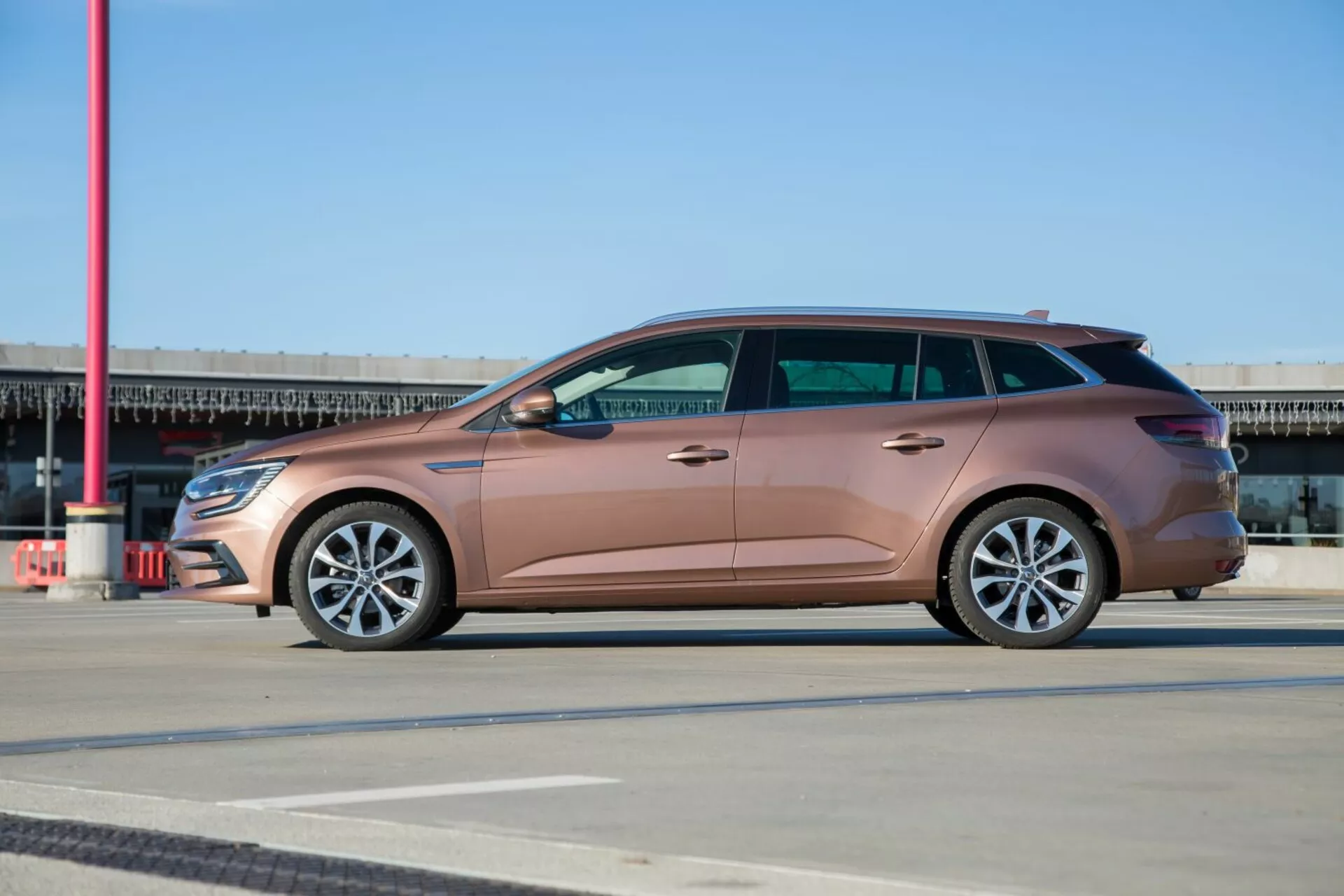 Vagón de estación Kia Ceed 2009 en rubor metálico, vista completa del perfil lateral en pavimento estampado, mostrando ruedas de aleación y diseño elegante bajo cielo azul claro