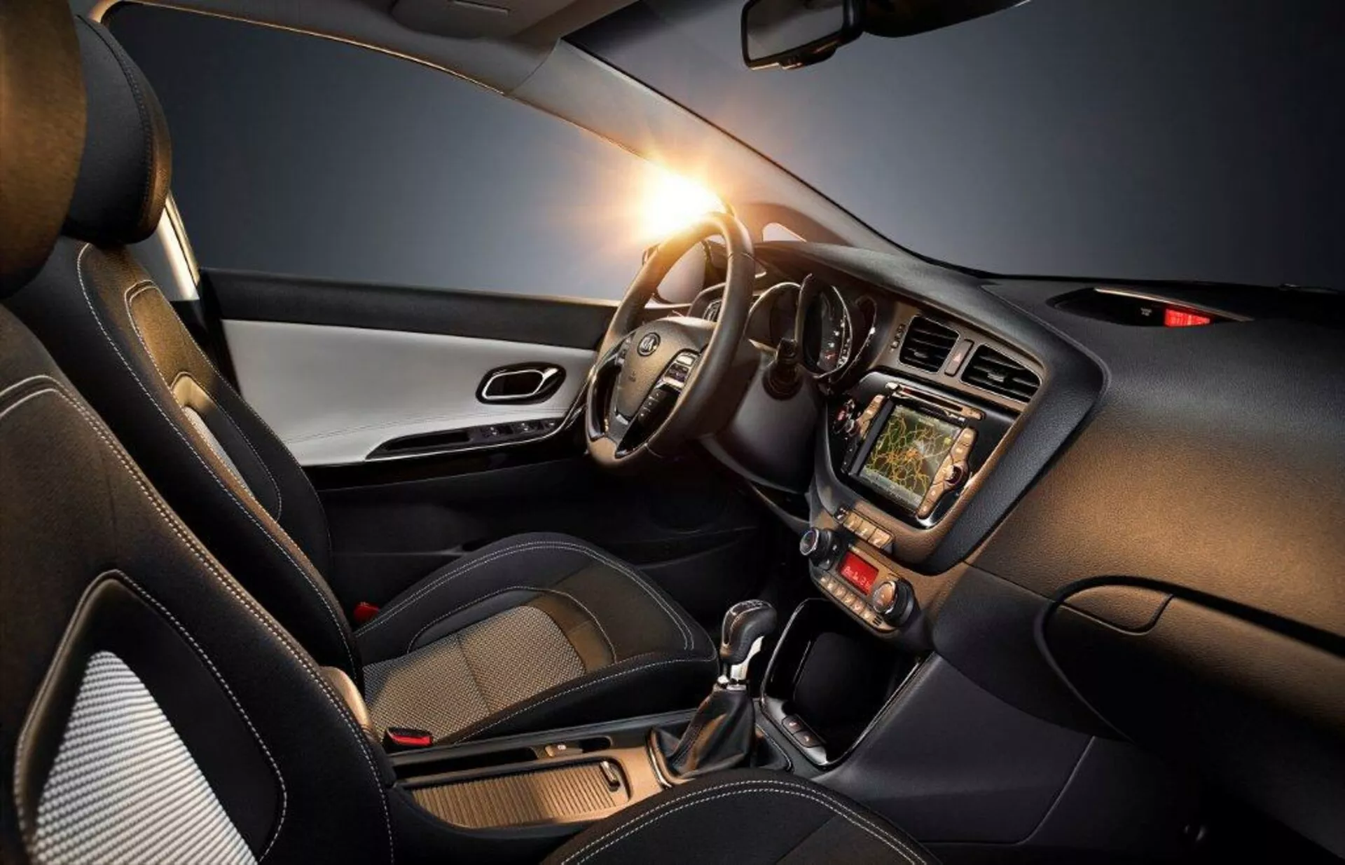 Interior del Kia Cee'd 2009 destacando el lado del conductor con volante a la izquierda, cuadro de instrumentos, sistema de infoentretenimiento táctil, controles de clima, palanca de cambios automática y acentos de diseño moderno, enfatizando la tecnología, comodidad y aspecto deportivo