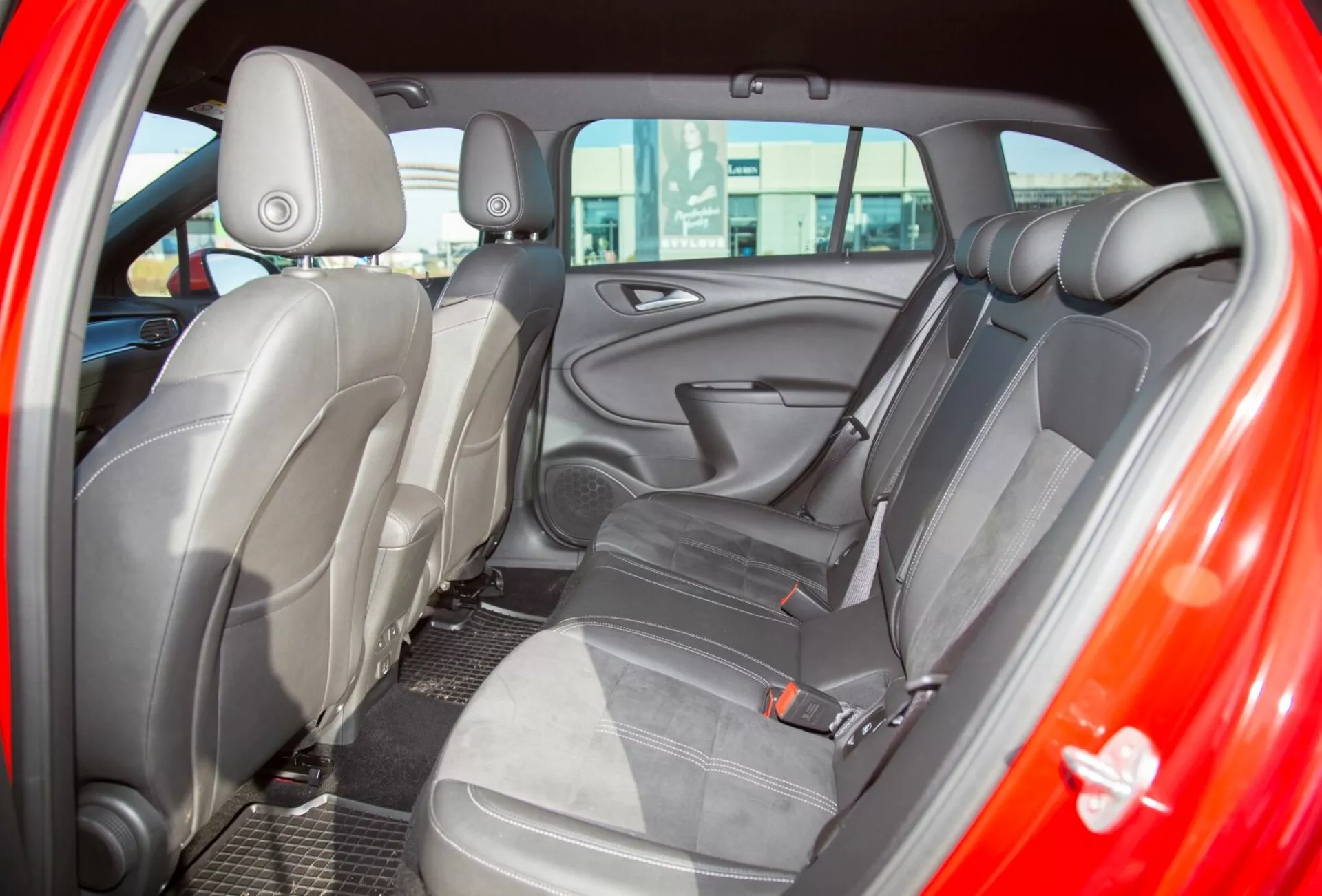 Vista detallada del interior de un Kia Ceed de 2009, mostrando el asiento trasero desde la puerta trasera del lado del conductor, destacando la tapicería de tela en dos tonos y el diseño ergonómico de los asientos para mayor comodidad