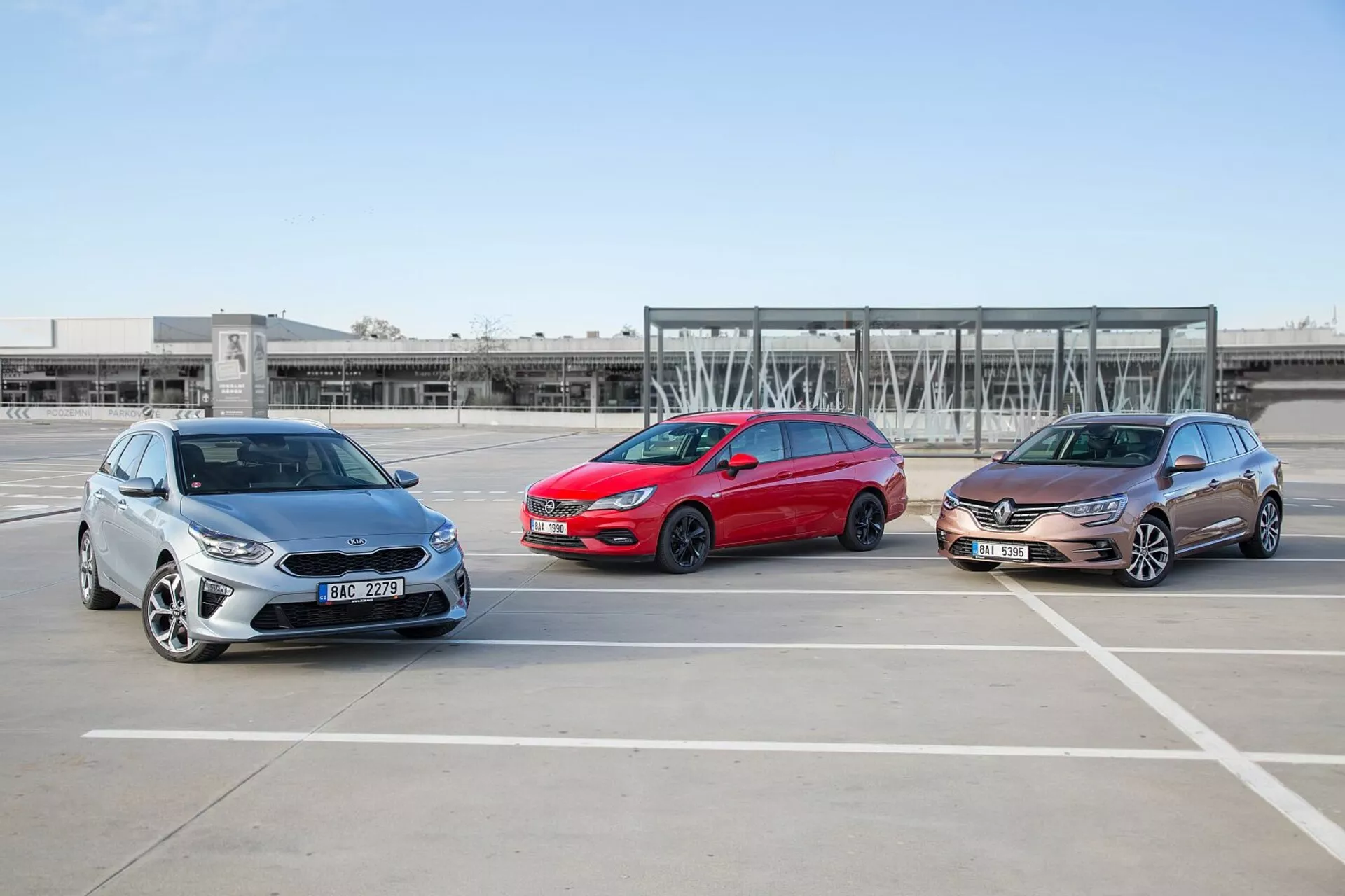 Tres modelos de Kia Ceed 2009, escalonados en formación en un estacionamiento vacío, mostrando sus perfiles frontales y laterales bajo condiciones climáticas claras