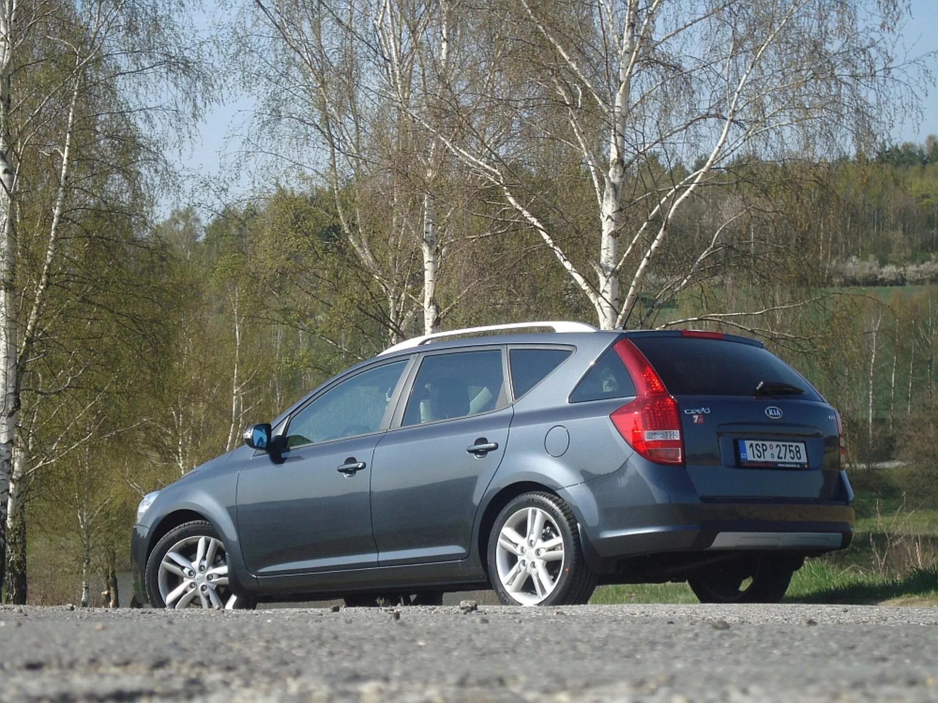 Vagoneta Kia Ceed 2009 en gris, mostrando el diseño lateral y trasero, con énfasis en la línea del techo aerodinámico, las luces traseras y la ventana trasera, estacionado al aire libre