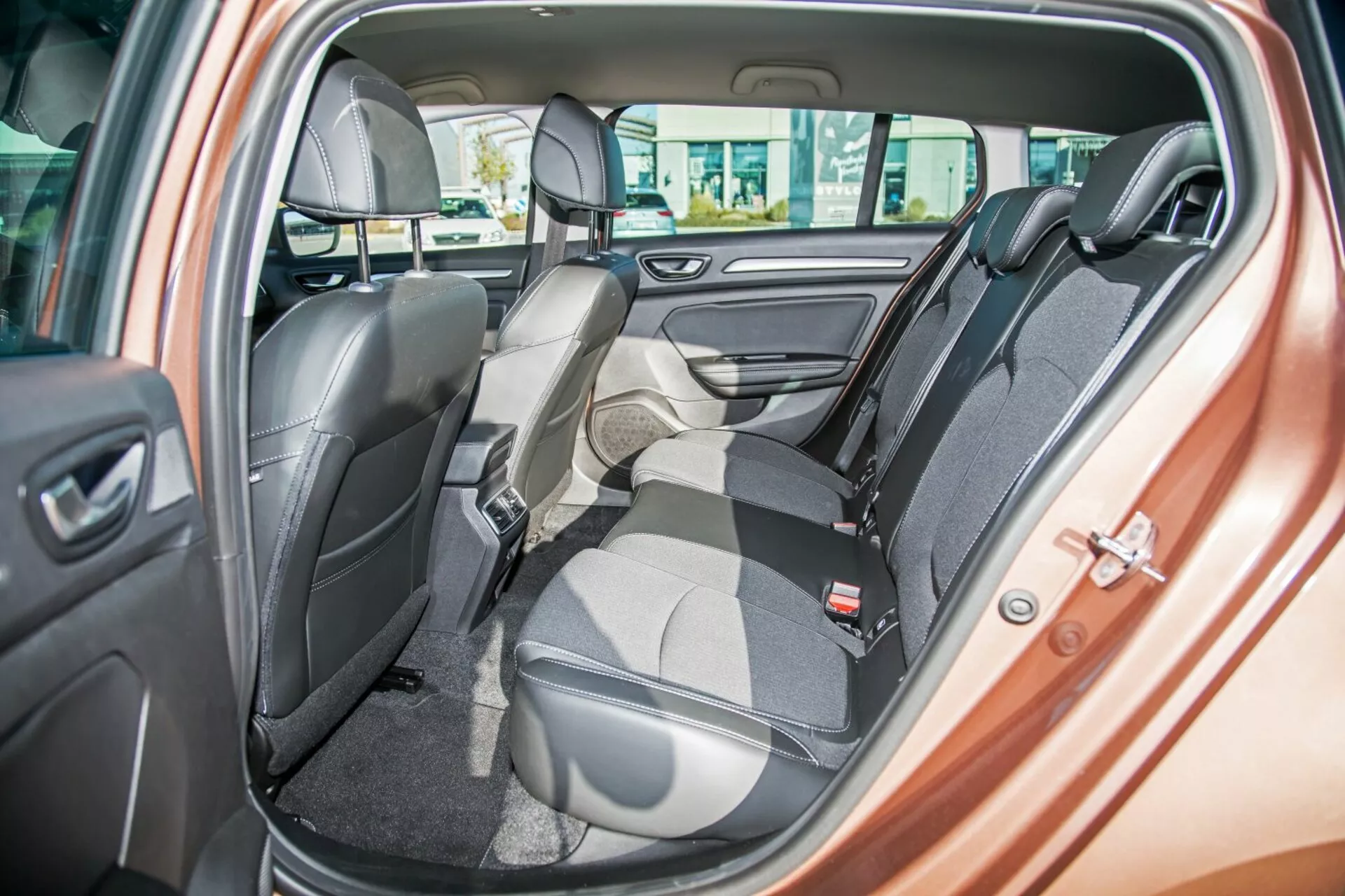 Interior del Kia Ceed 2009 mostrando el asiento trasero de dos tonos con un asiento plegado hacia adelante para carga, cinturones de seguridad, reposacabezas, controles de ventanas eléctricas y altavoz en la puerta, destacando asientos flexibles y diseño de lujo