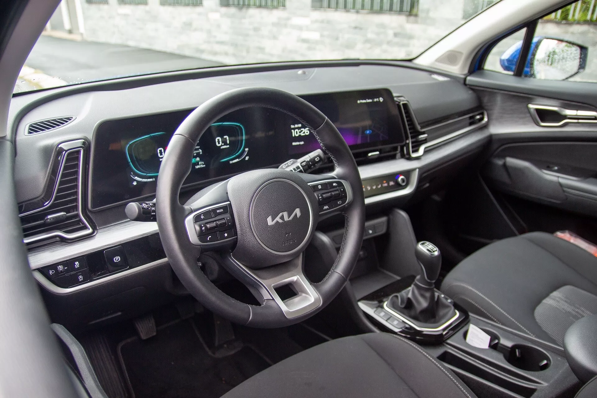 Interior del Kia Sportage 2022 mostrando el volante con botones de control, el cuadro de instrumentos digital y la pantalla de infotenimiento