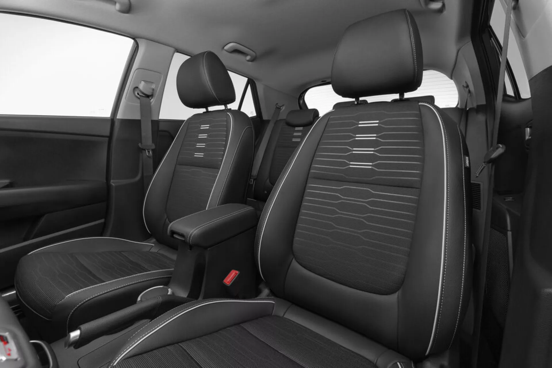 Vista en ángulo alto del interior frontal del Kia Stonic 2017 mostrando asientos de cuero negro con costuras horizontales, consola central y puntos de bloqueo de cinturón de seguridad rojos enfocados en diseño y distribución