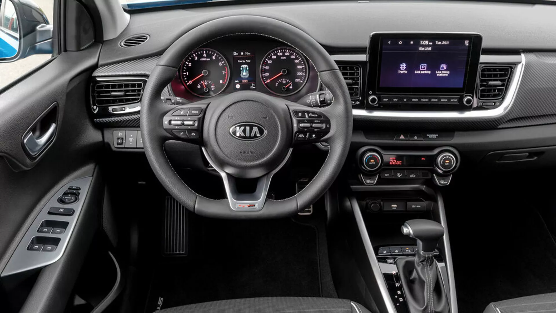 Vista interior de un Kia Stonic 2017 desde la perspectiva del pasajero, con volante de tres radios con controles montados, cuadro de instrumentos analógico-digital, sistema de infotenimiento táctil, control climático, transmisión automática y selector de modo de conducción.