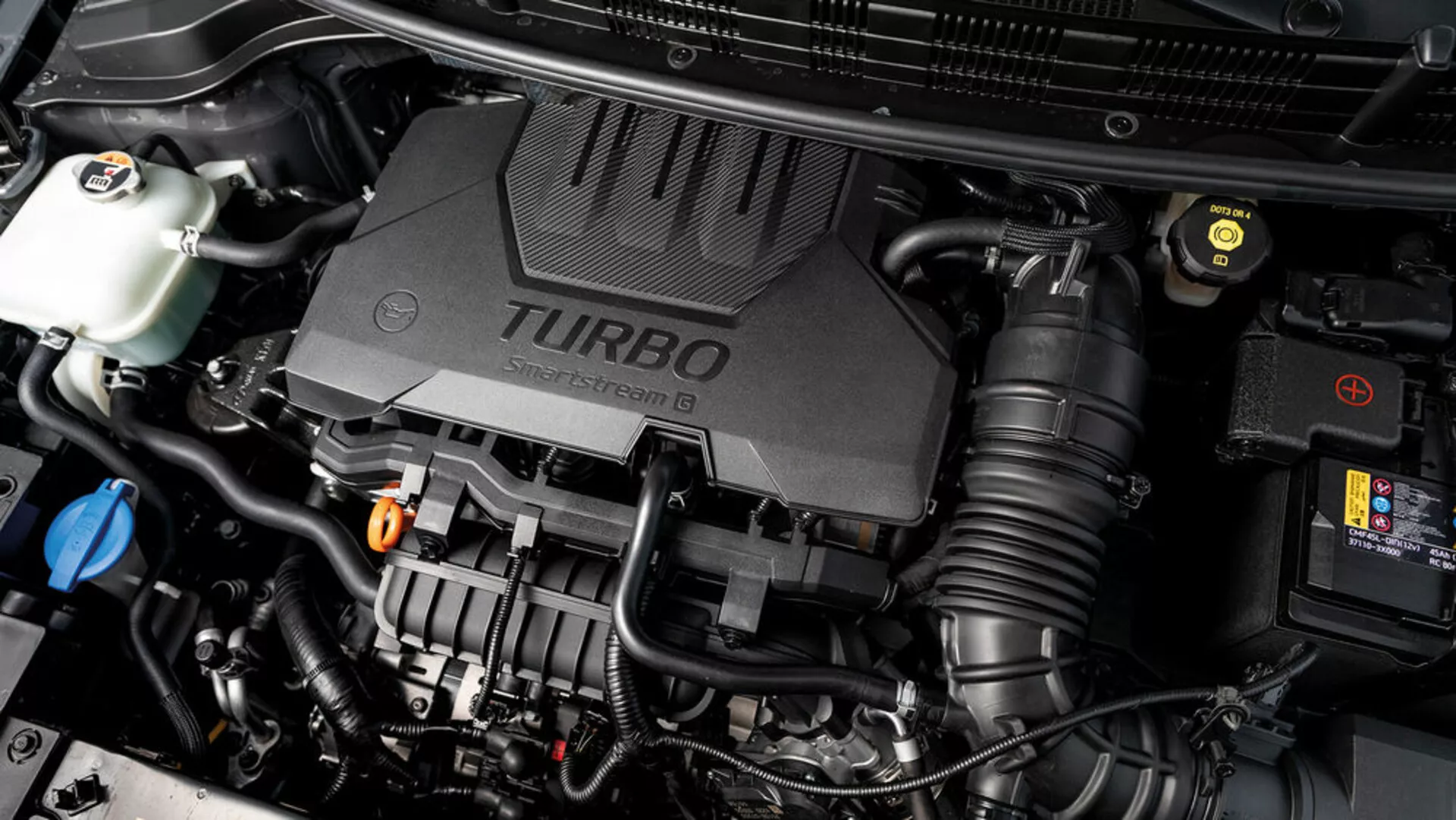 Vista cercana del compartimento del motor de Kia Stonic 2017 con cubierta de motor turboalimentado y varios componentes mecánicos visibles, mostrando aspectos tecnológicos del vehículo