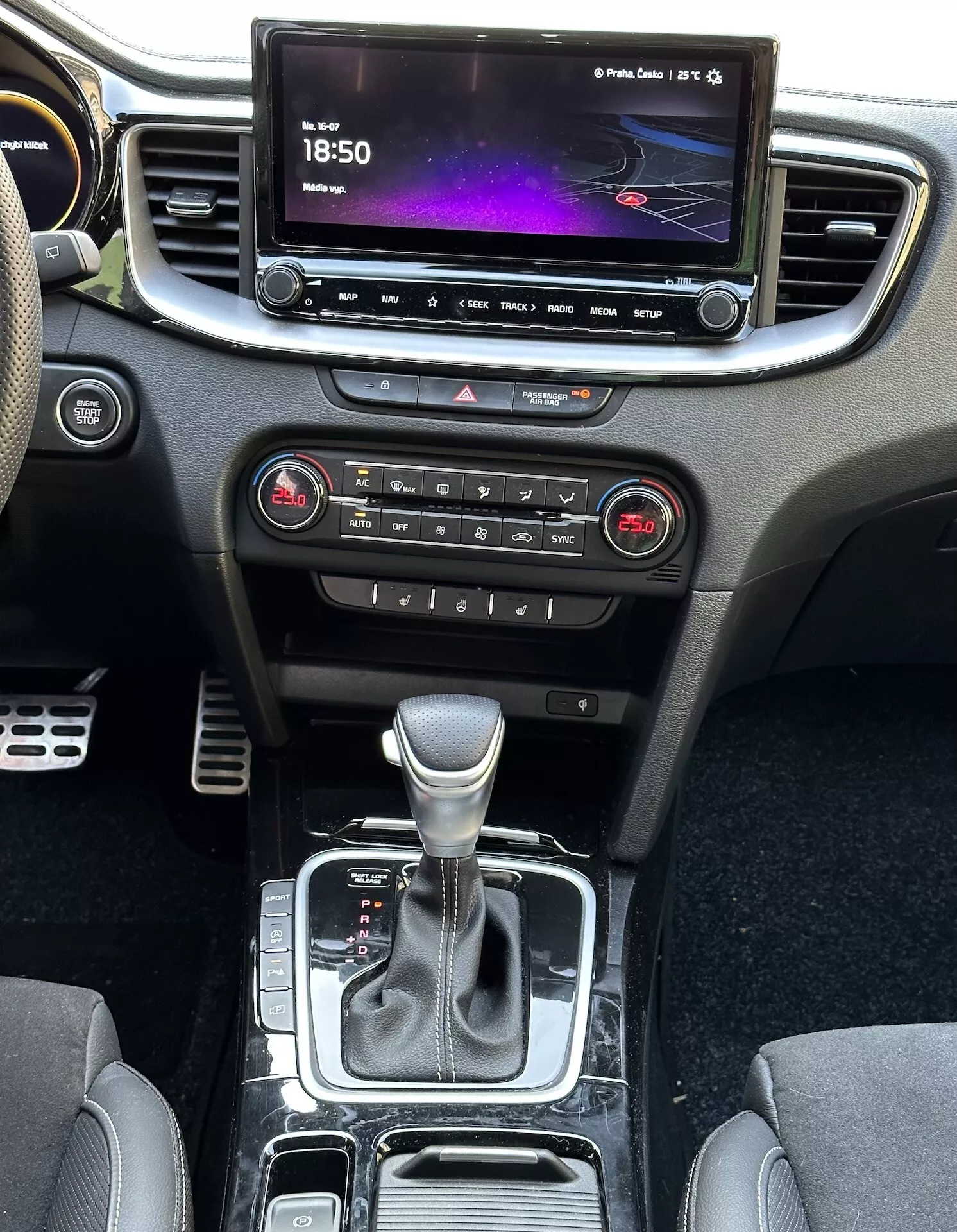 Vista interior del Kia Xceed 2022 mostrando la consola central, el tablero de instrumentos, la pantalla de infoentretenimiento, los botones de control climático, la palanca de cambios y las áreas de almacenamiento, destacando la tecnología moderna y el diseño del vehículo.