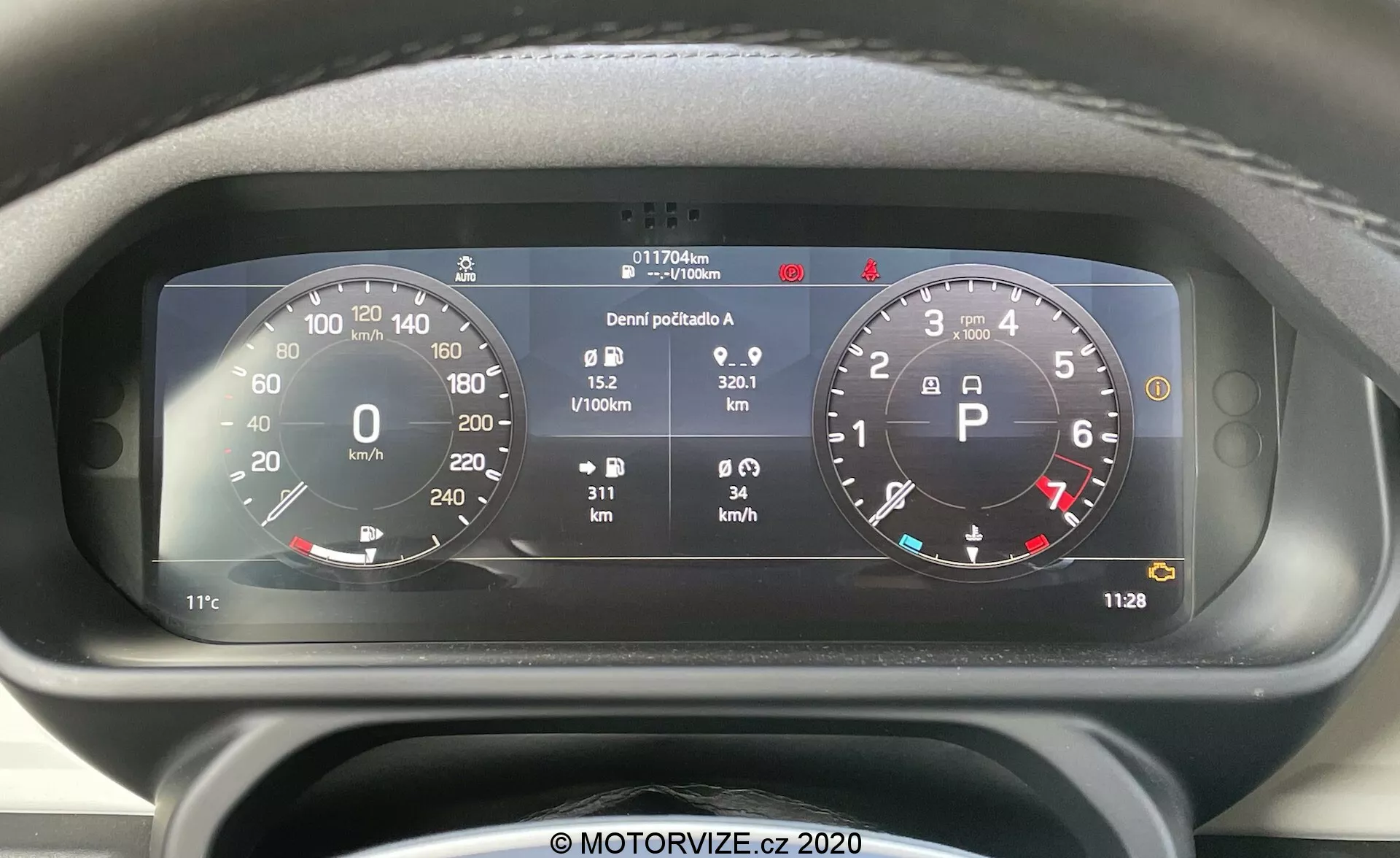 Vista frontal de cerca del panel de instrumentos digital del Land Rover Defender 2020 con un destacado velocímetro circular (0-260 km/h) y tacómetro (0-8,000 RPM), integración de varios indicadores de estado del vehículo e información detallada que incluye medidor de combustible, temperatura, odómetro (117,706 km), contadores de viajes, consumo medio de combustible (0.9 L/100km), velocidad media (32.1 km/h) y reloj digital (11:28).