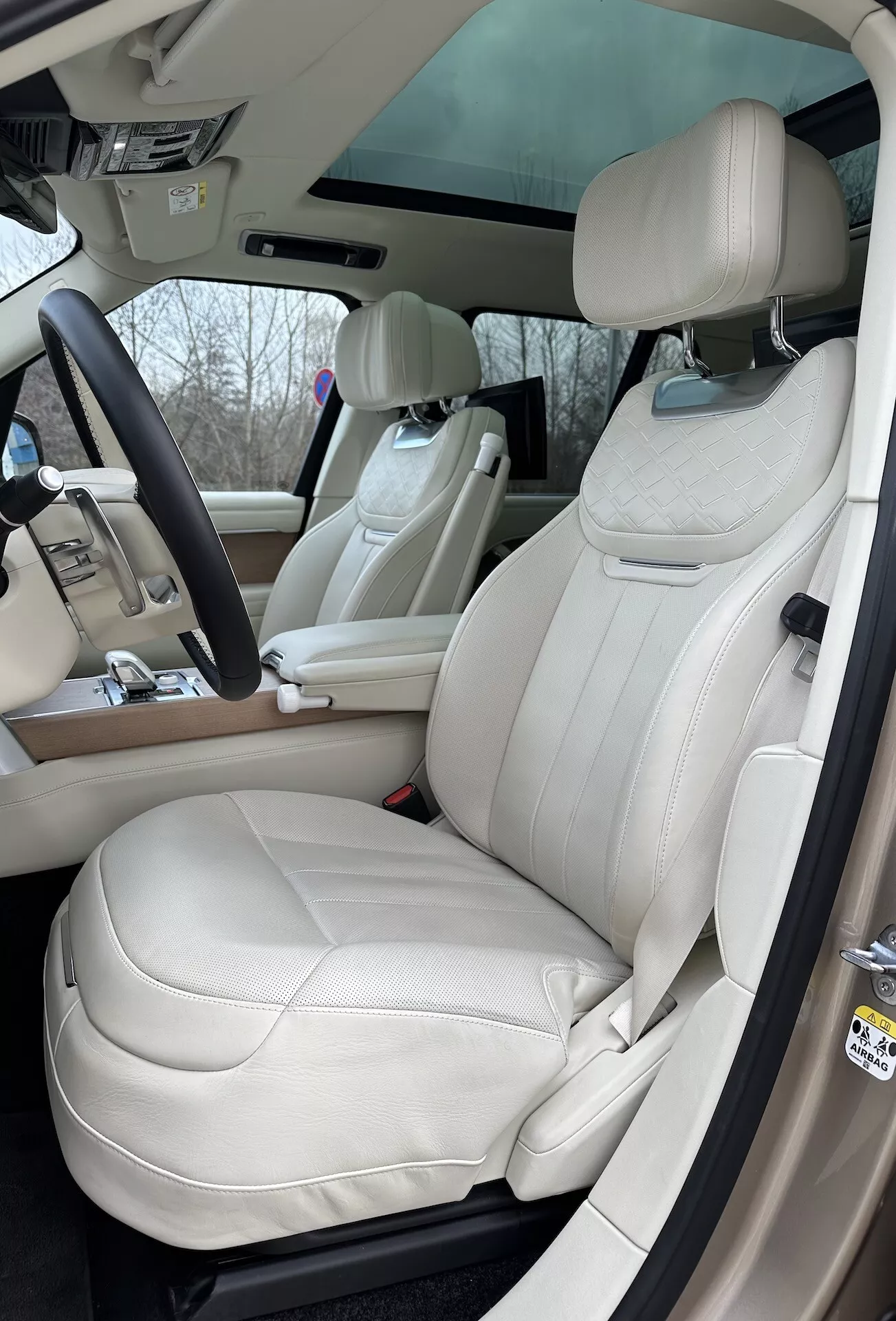 Vista interior del Land Rover Range Rover 2021 destacando el lado del conductor con asientos de cuero crema de lujo, volante multifunción y elementos de control avanzados en la consola central