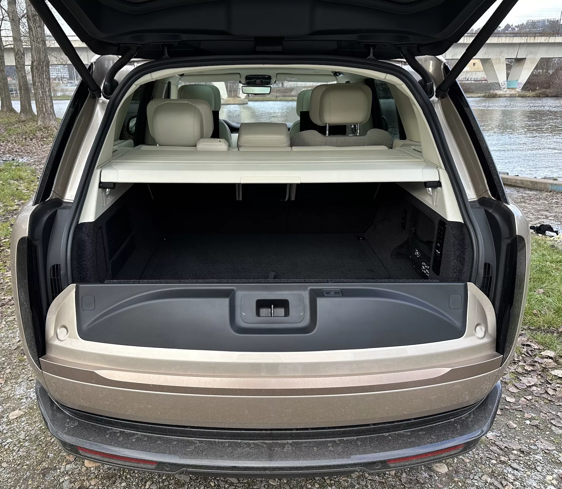 Vista trasera del Land Rover Range Rover 2021 con hatchback abierto mostrando el espacioso área de carga, iluminación avanzada, y toma de corriente de 12 voltios contra un entorno de luz natural al aire libre