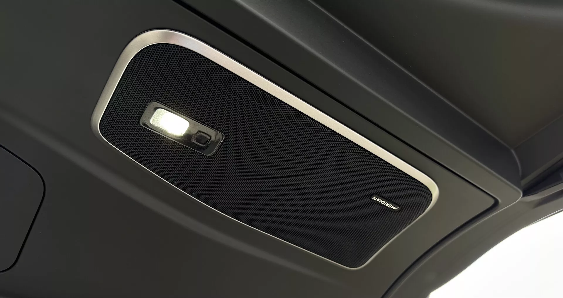 Vista detallada de la consola superior interior del Range Rover 2021, mostrando una rejilla de altavoz de alta calidad y luz domo, enfatizando la acústica de cabina premium y la tecnología avanzada de iluminación interior.
