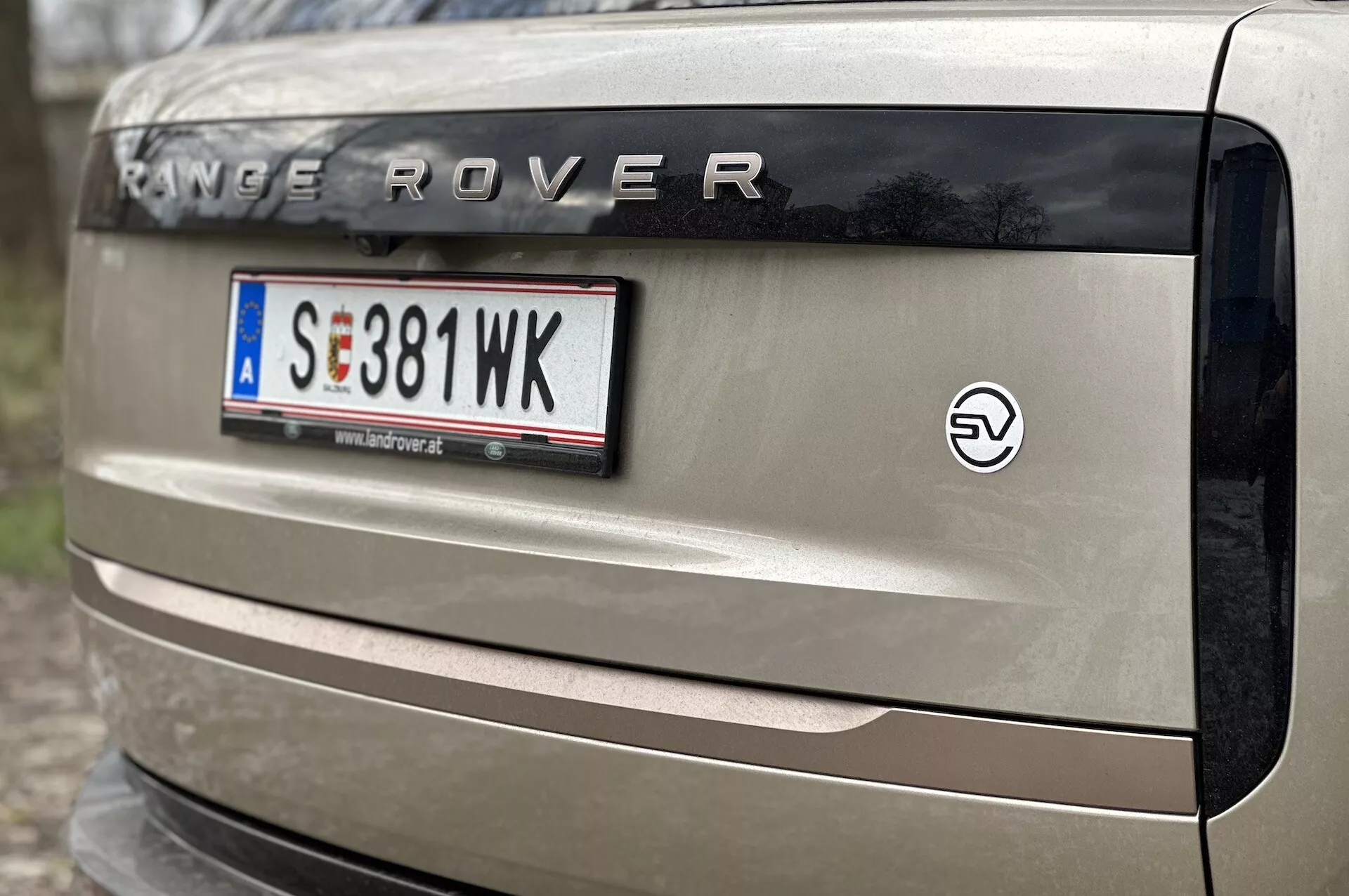 Vista de cerca de la parte trasera de un Range Rover 2021 mostrando la marca 'RANGE ROVER', matrícula al estilo europeo, emblema EV y parte de la luz trasera